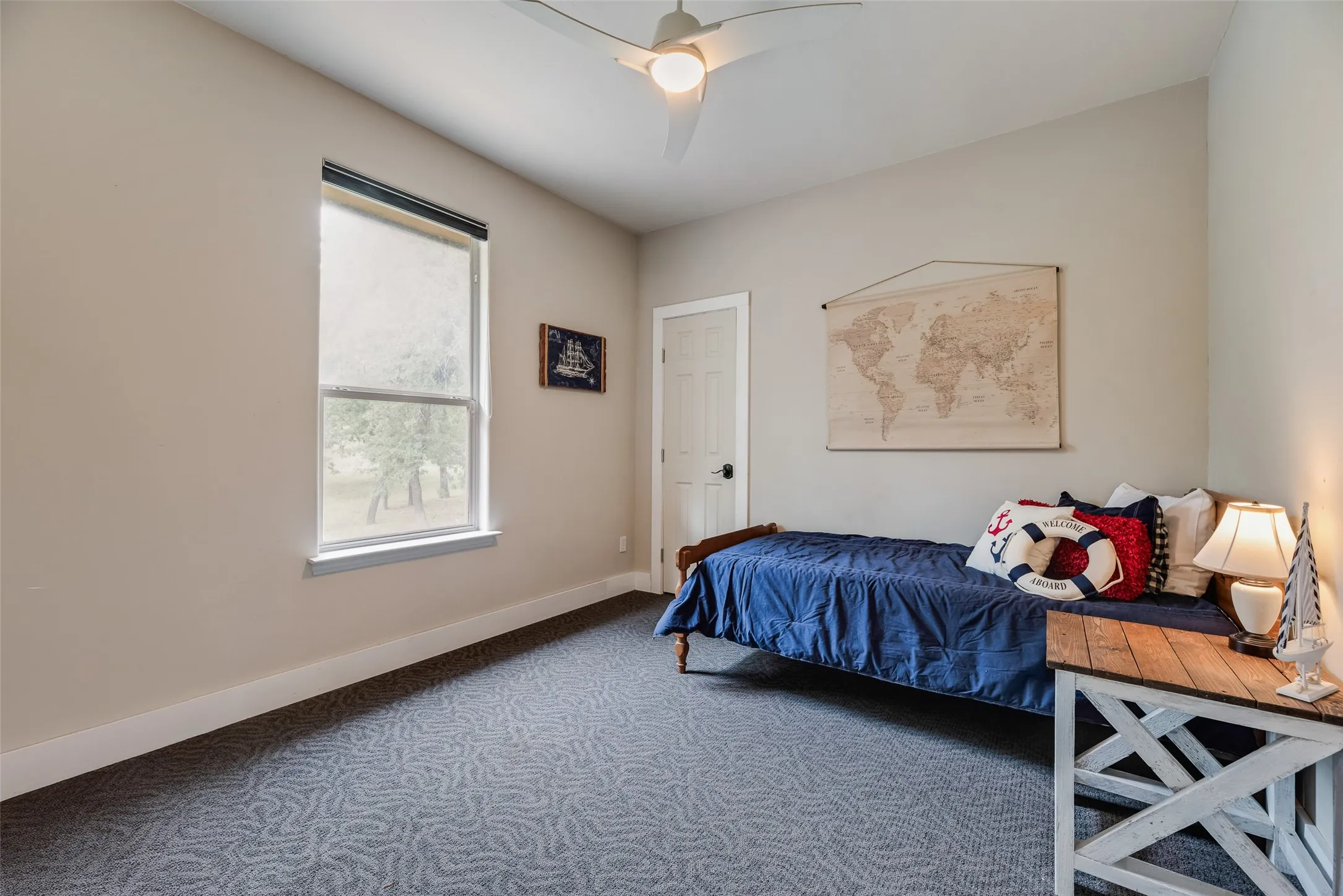 Room featuring patterned carpeting, neutral wall paint, and a white ceiling fan with integrated lighting