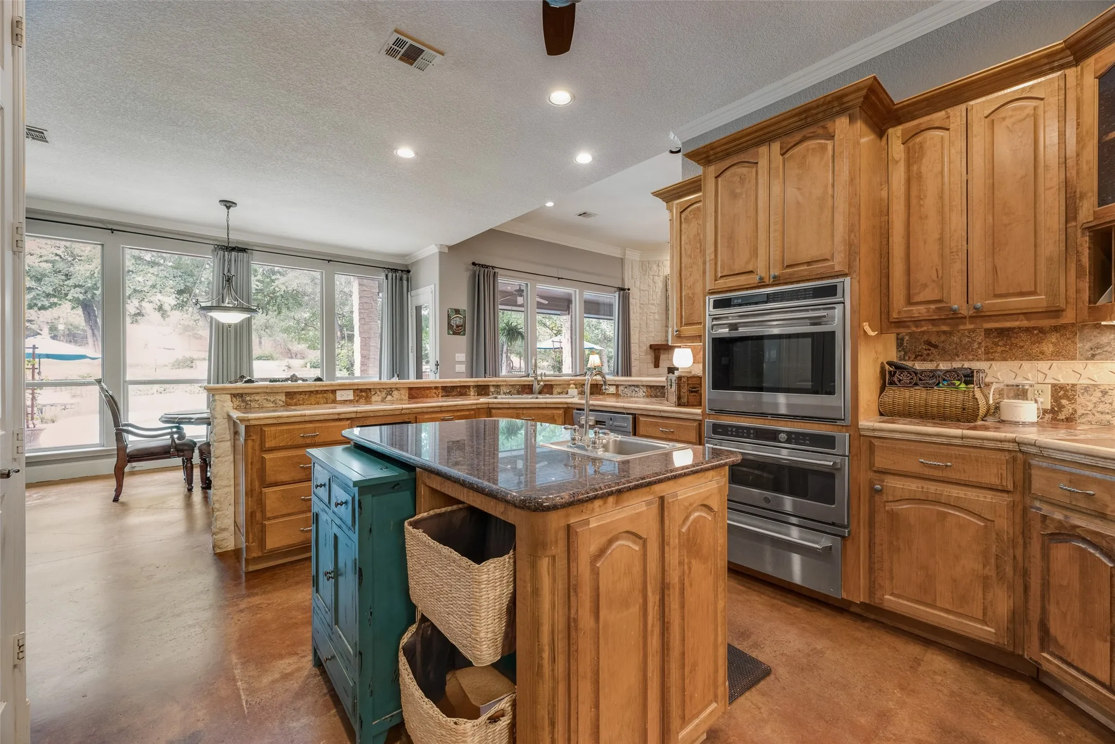 Kitchen featuring wood cabinetry, stainless steel double wall ovens, granite countertops, and a stone-tiled backsplash