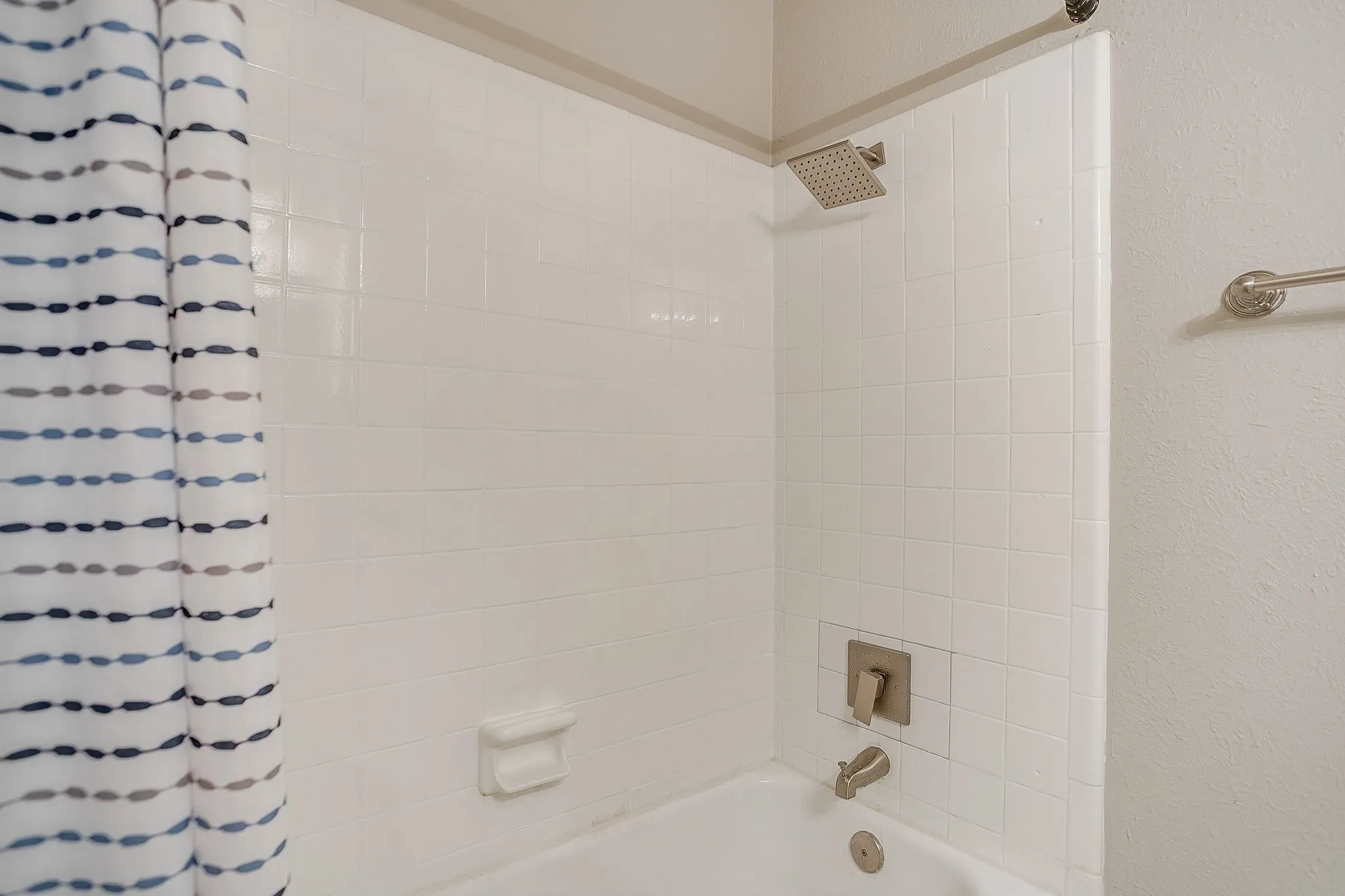 White subway tile shower surround featuring a rainfall showerhead and brushed nickel fixtures