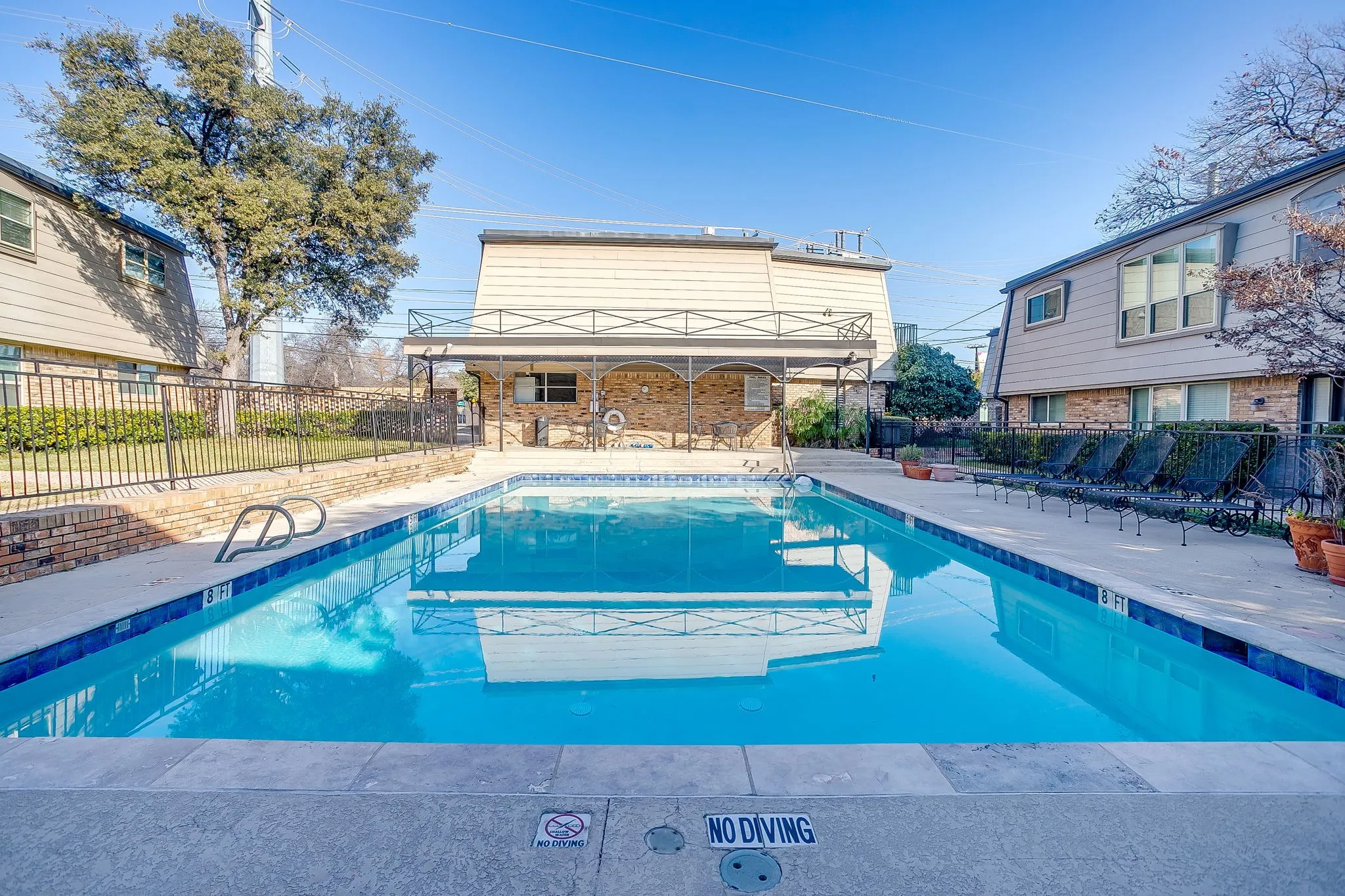 Outdoor swimming pool featuring a perimeter of concrete decking and a dark blue waterline tile band