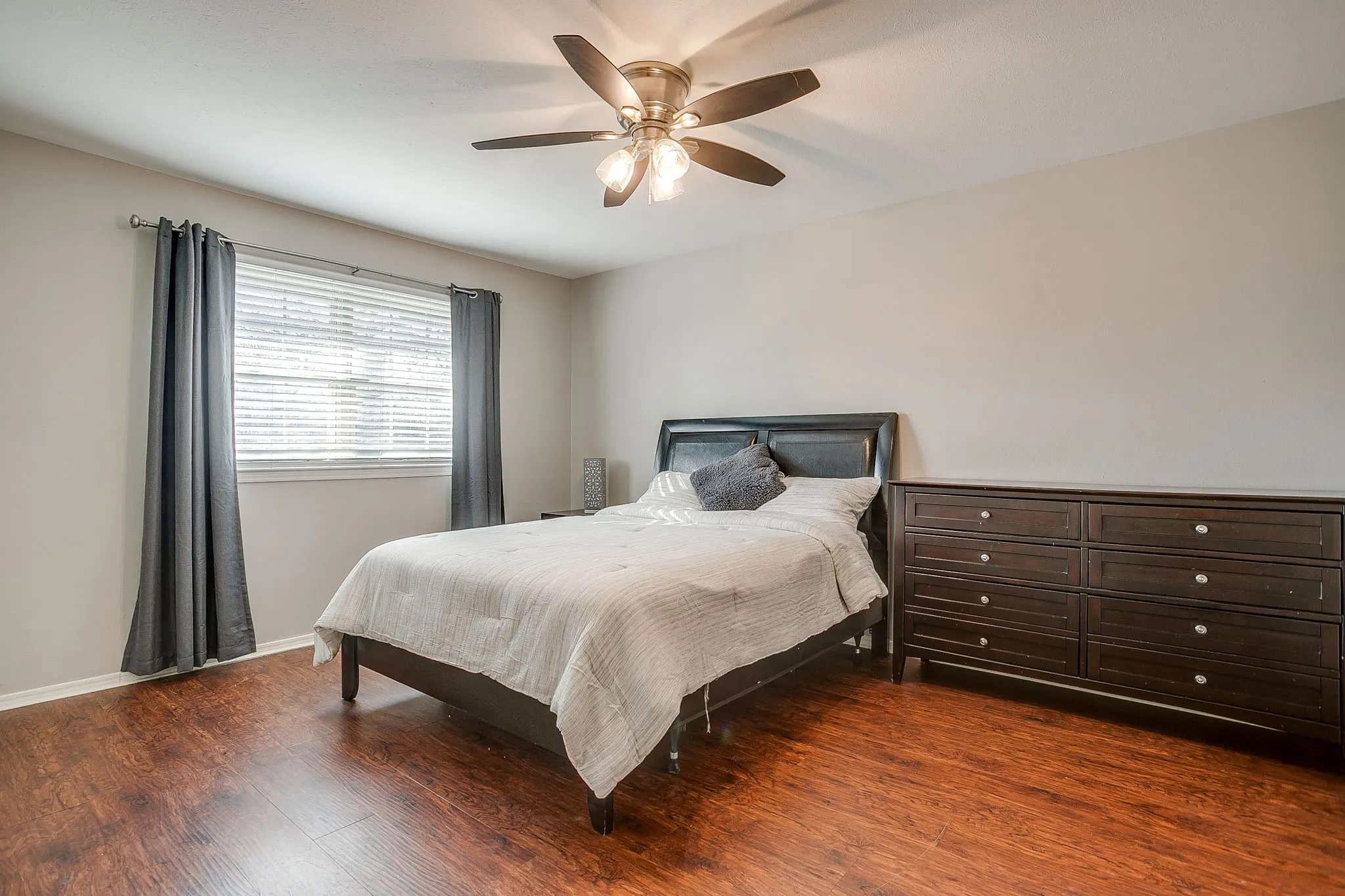 Bedroom featuring wood-finish flooring, a ceiling fan with integrated lighting, and neutral wall tones