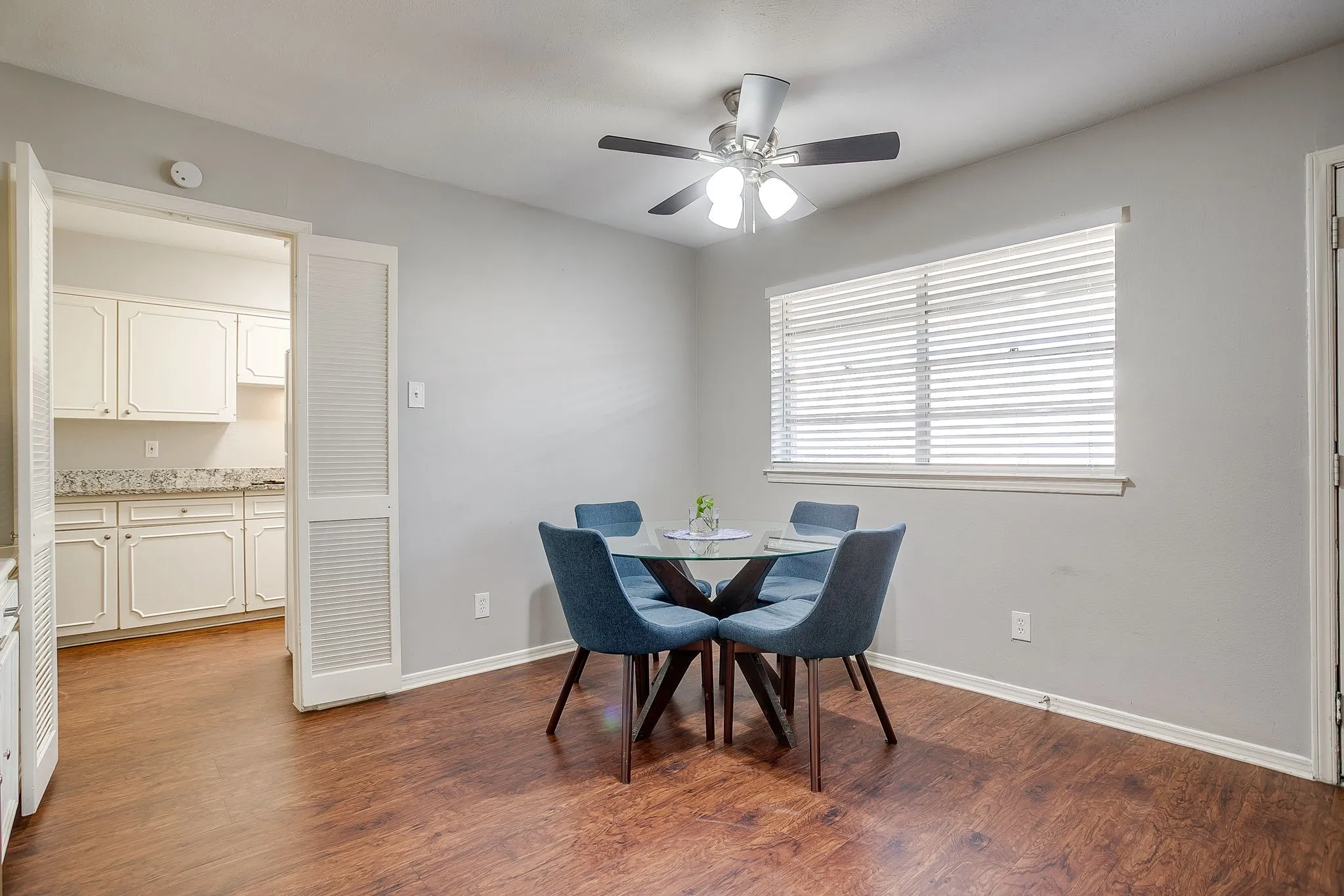 Dining area featuring wood-finish flooring, a ceiling fan with integrated lighting, and a window with blinds
