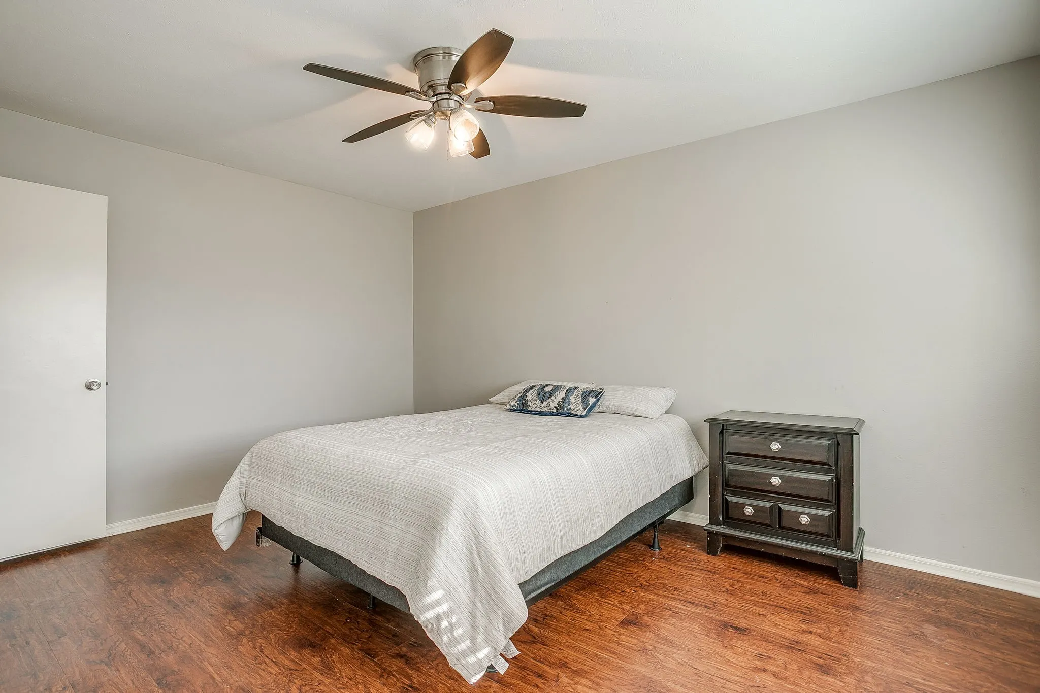 Bedroom featuring wood-finish flooring, neutral wall tones, and a ceiling fan with integrated lighting