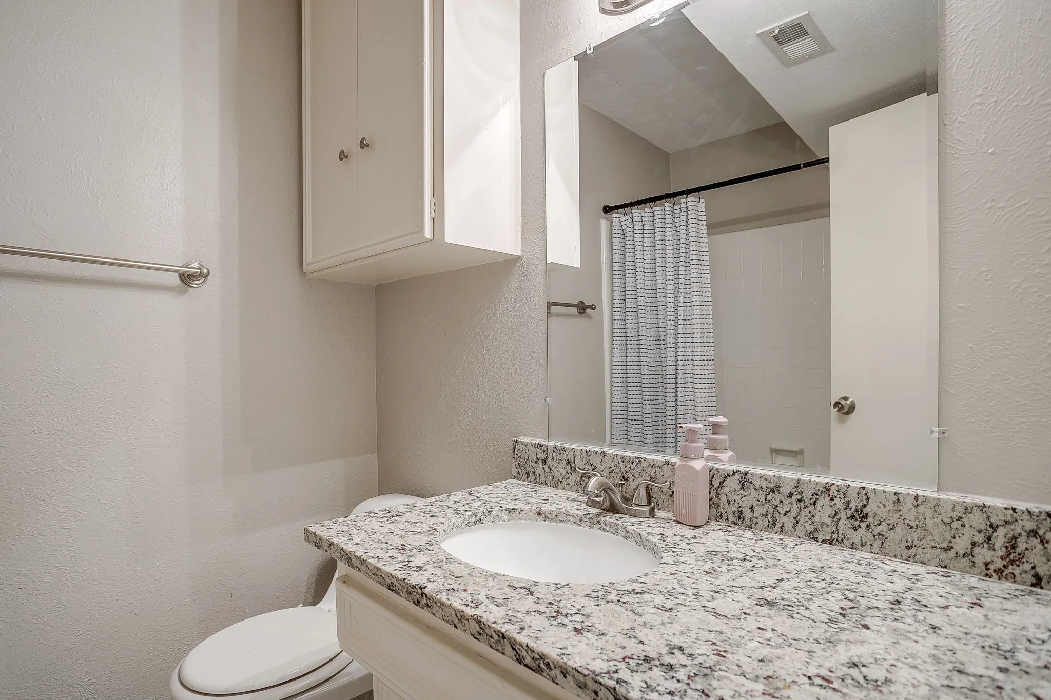 Bathroom vanity featuring a light-toned granite countertop, undermount sink, and a large wall-mounted mirror