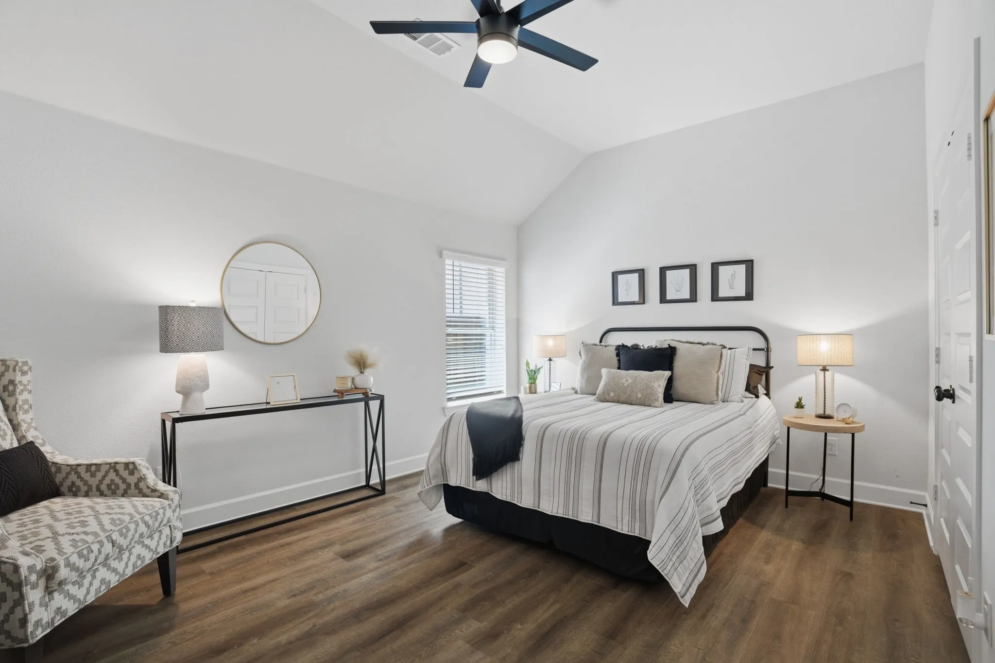 Secondary bedroom showcasing vaulted ceilings, attractive wood-look flooring, and a practical ceiling fan for comfortable climate control.