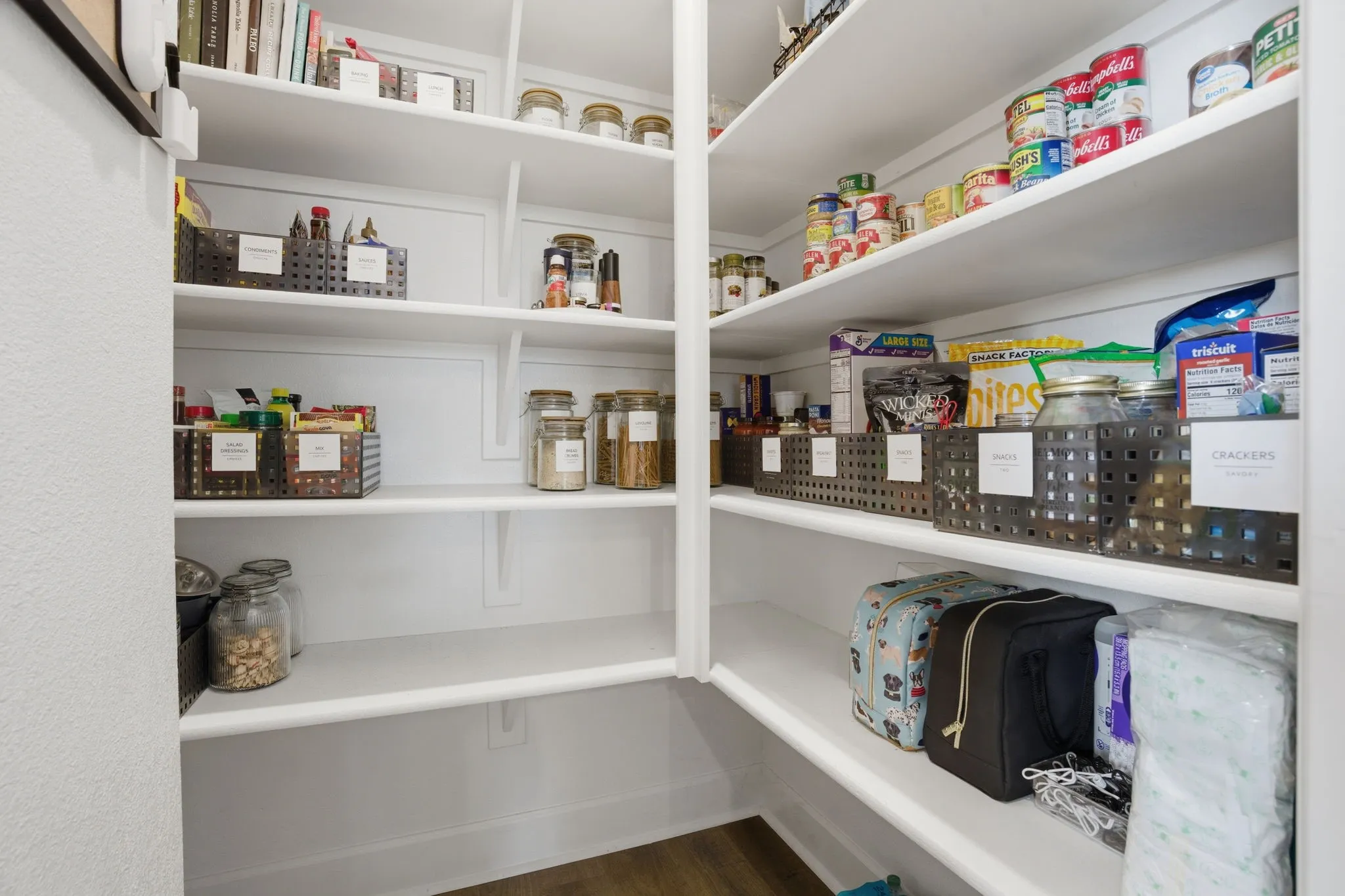 Detailed view of a spacious walk-in pantry, featuring abundant and strategically organized shelving designed for optimal storage, complemented by clean, bright white painted finishes that enhance the sense of openness and functionality within the space.