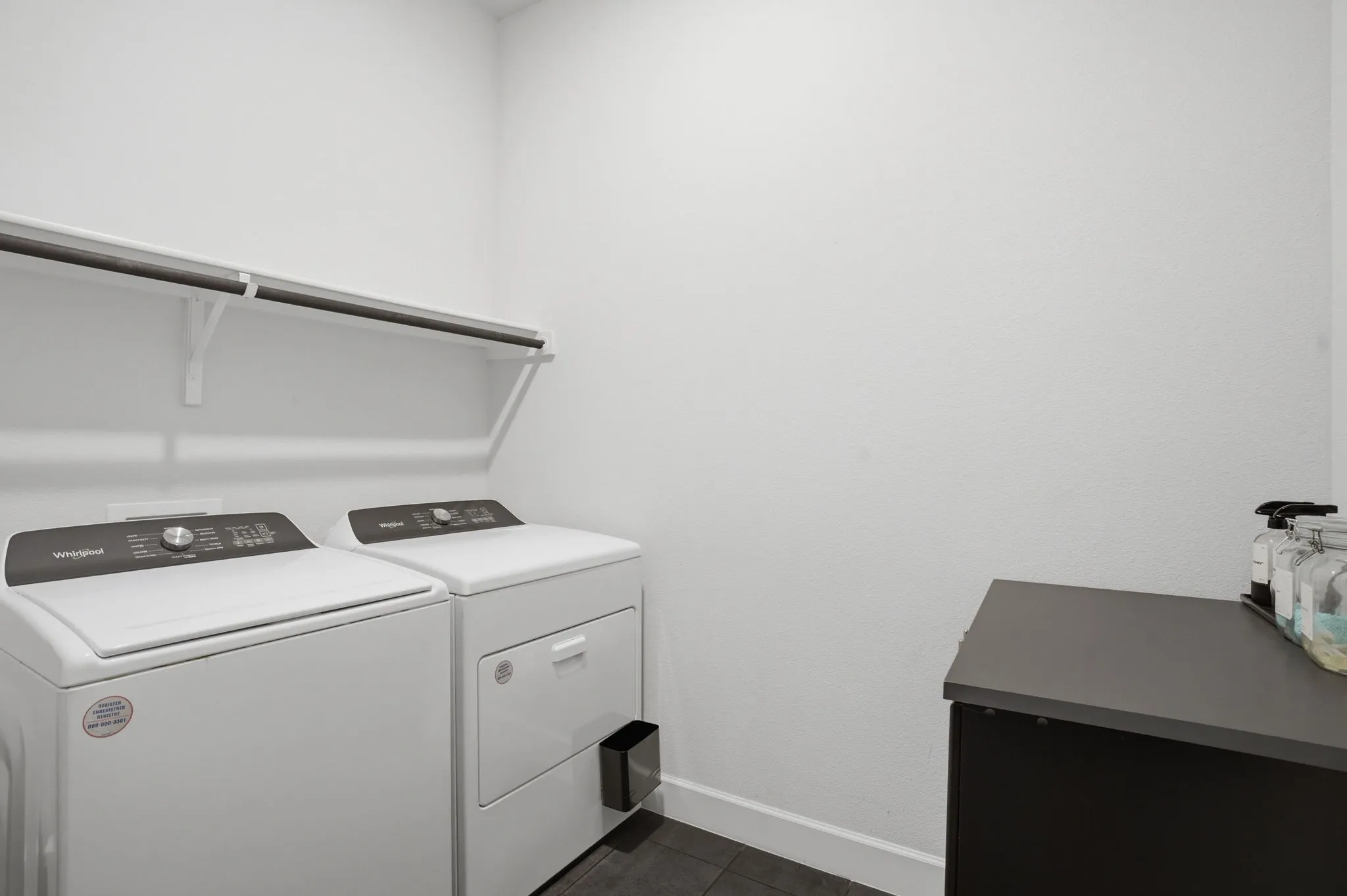 Well-designed space, featuring a dedicated area specifically set aside for laundry needs, along with the added convenience of wall-mounted shelving for organized storage, and ample room accommodated for the installation of a second refrigerator, making it ideal for a home that values both practicality and extra storage options.