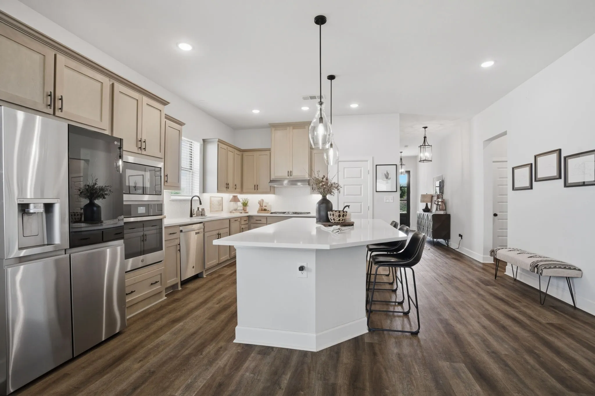 Here is another perspective showcasing the spacious, open-concept kitchen, highlighting the elegant stainless steel appliance package, and the expansive central island, which features a convenient and functional walk-in pantry for enhanced storage solutions.