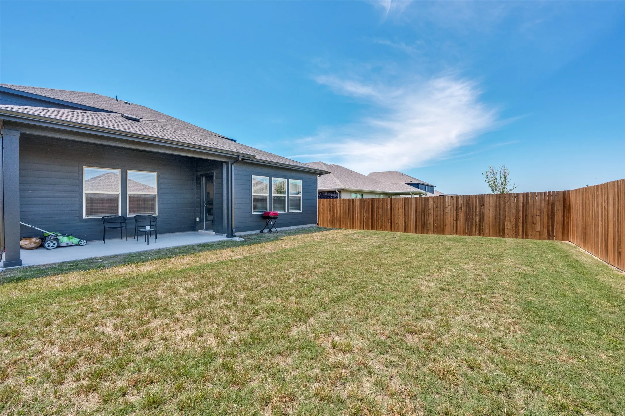 Spacious backyard featuring a full-height wood fence, a large concrete patio, and dark siding on the home's exterior