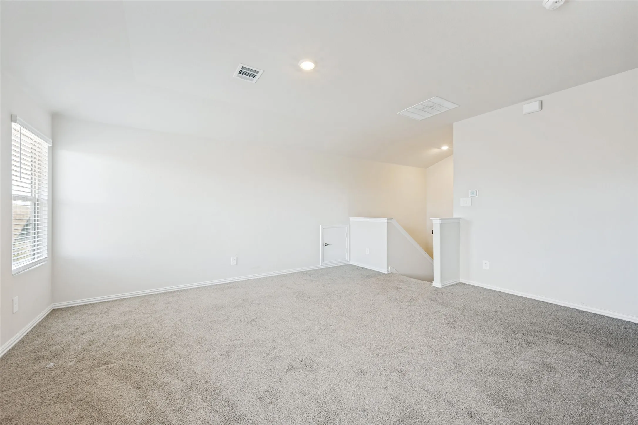 Spacious carpeted game room featuring white walls, recessed lighting, and a window with horizontal blinds