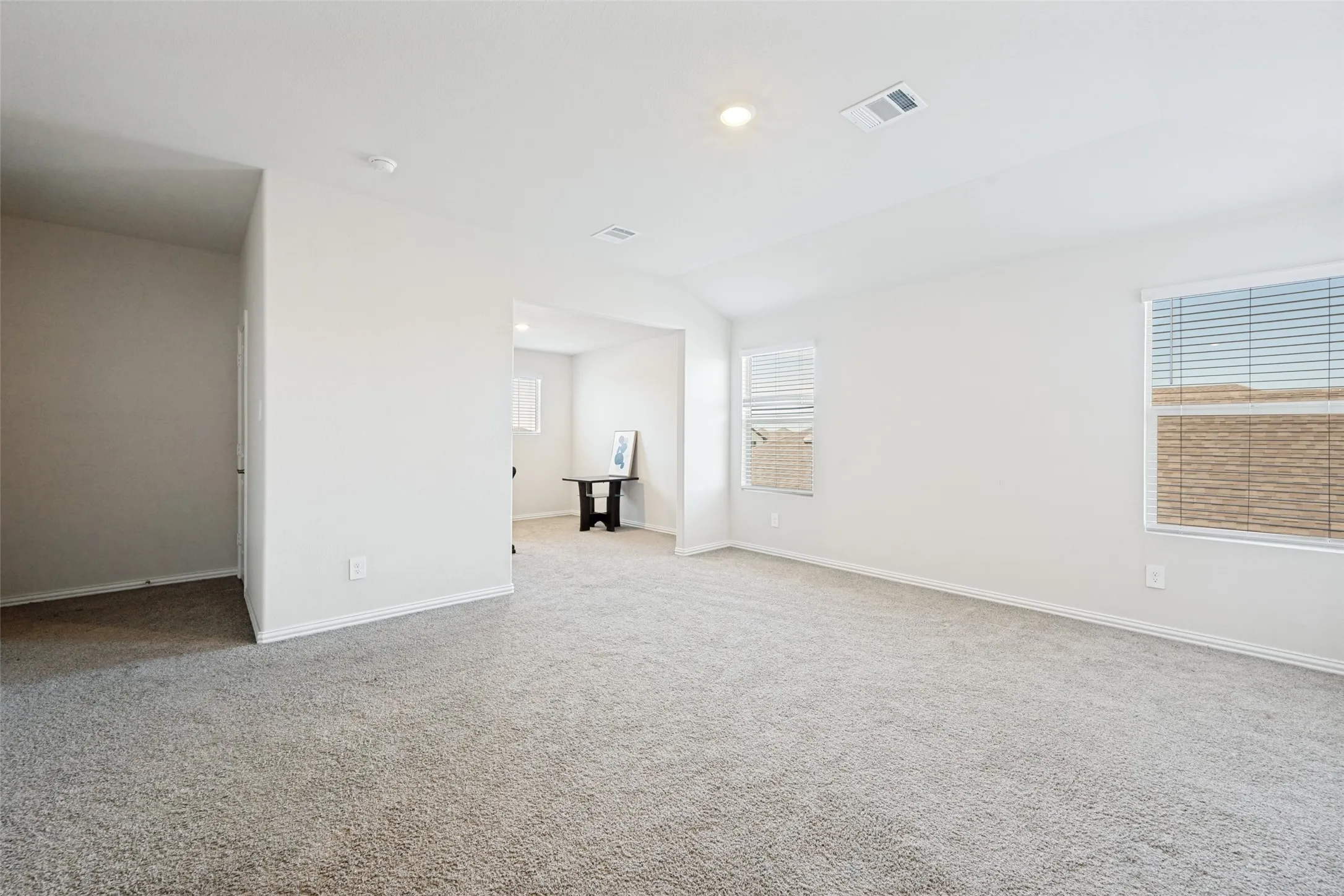 Spacious room featuring light gray carpet, white painted walls, and white trim
