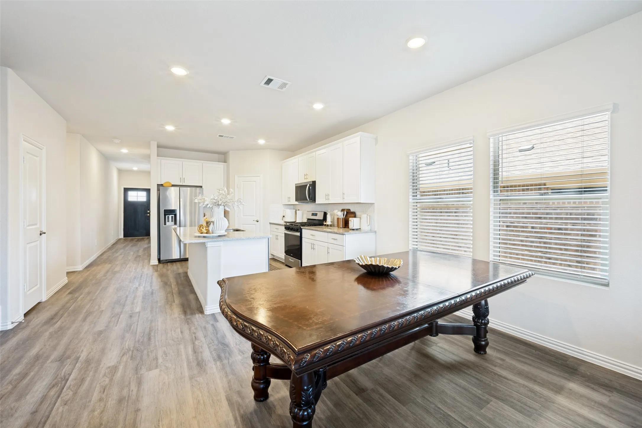 Open-concept living space featuring wood-finish flooring, recessed lighting, and crisp white walls