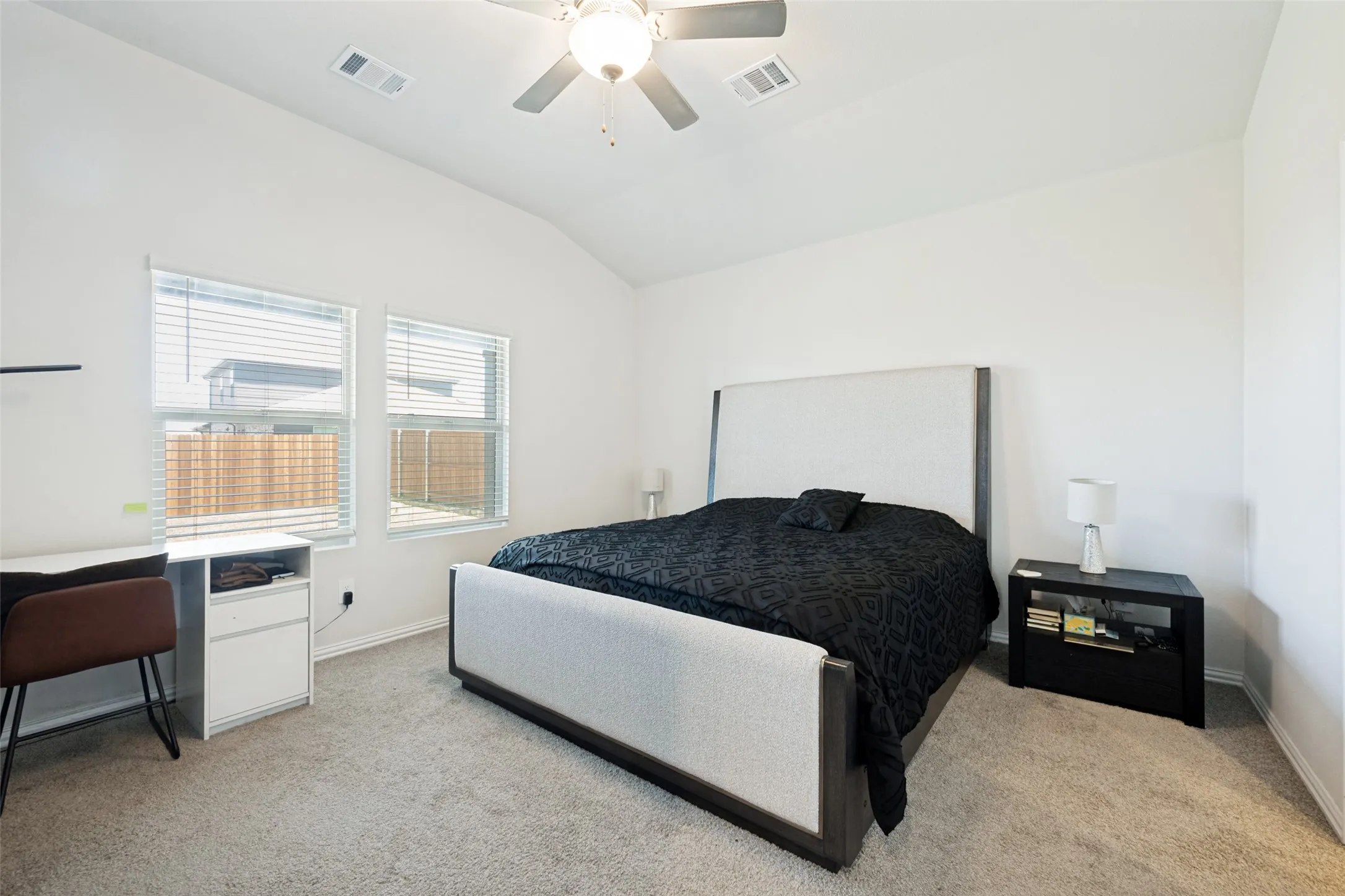 Carpeted room featuring a vaulted ceiling and a ceiling fan with light fixture