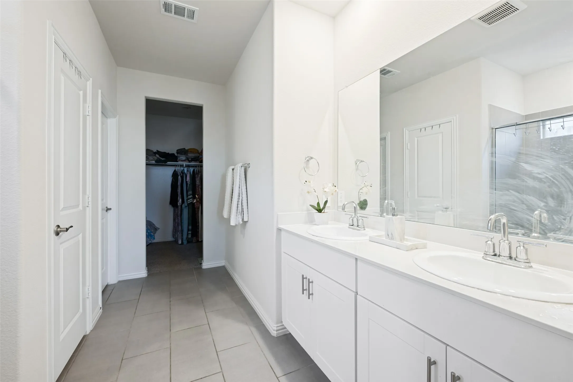 Bathroom featuring a dual vanity with white cabinetry, light-toned countertops, and two undermount sinks