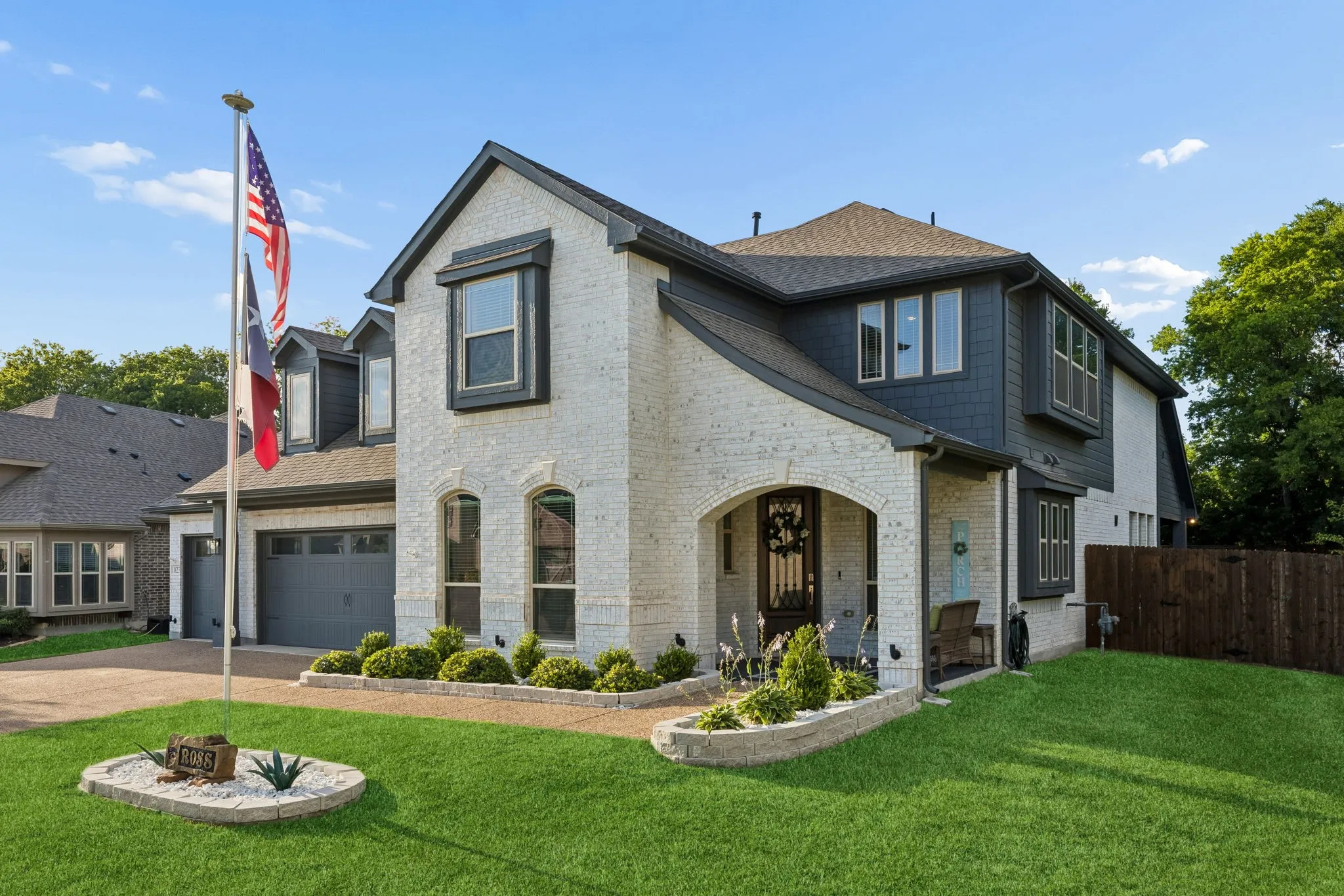 Two-story residence featuring a white brick and dark gray siding exterior