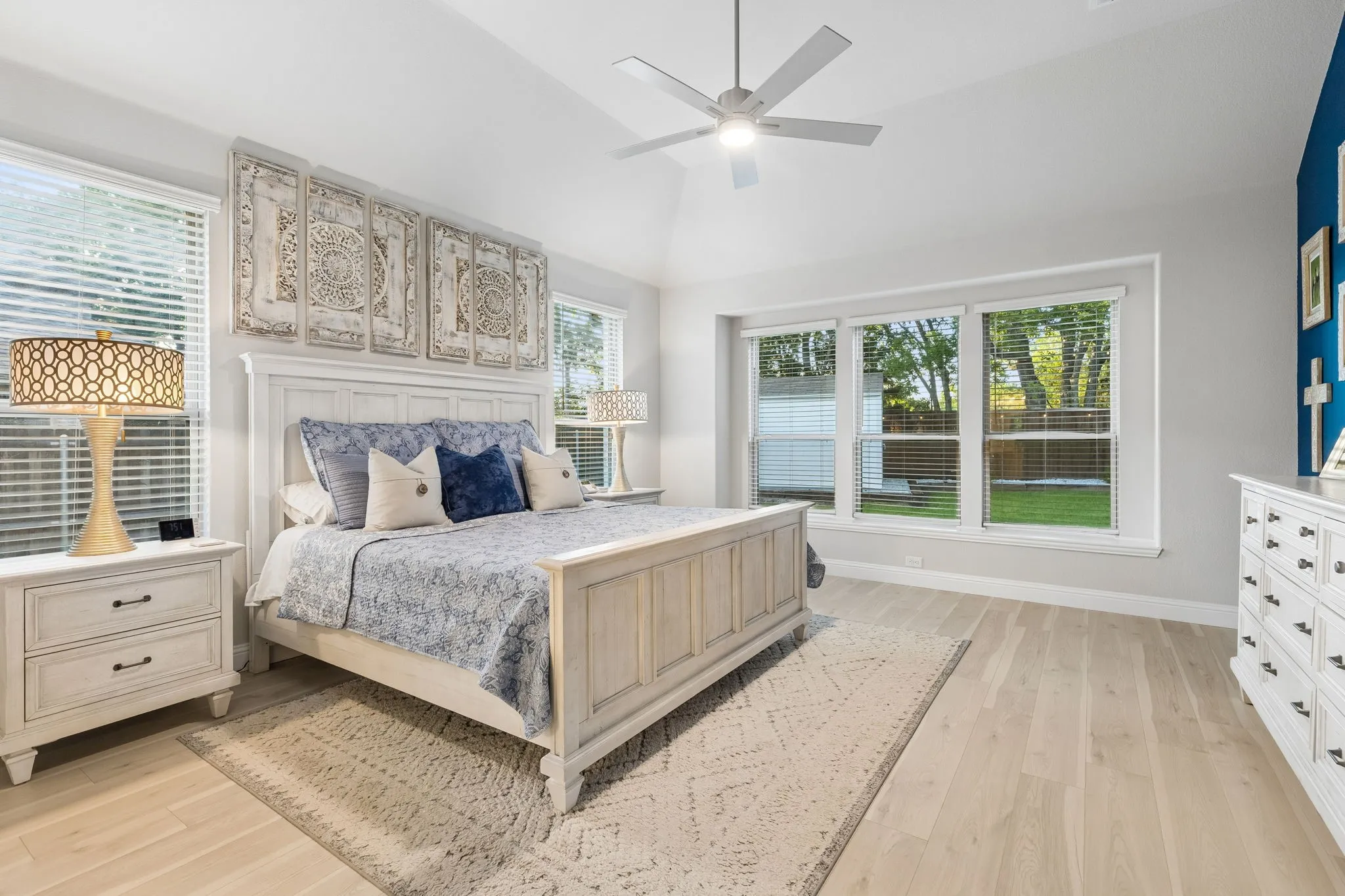 Primary Spacious bedroom featuring light wood-finish flooring, vaulted ceilings, and a ceiling fan with integrated lighting