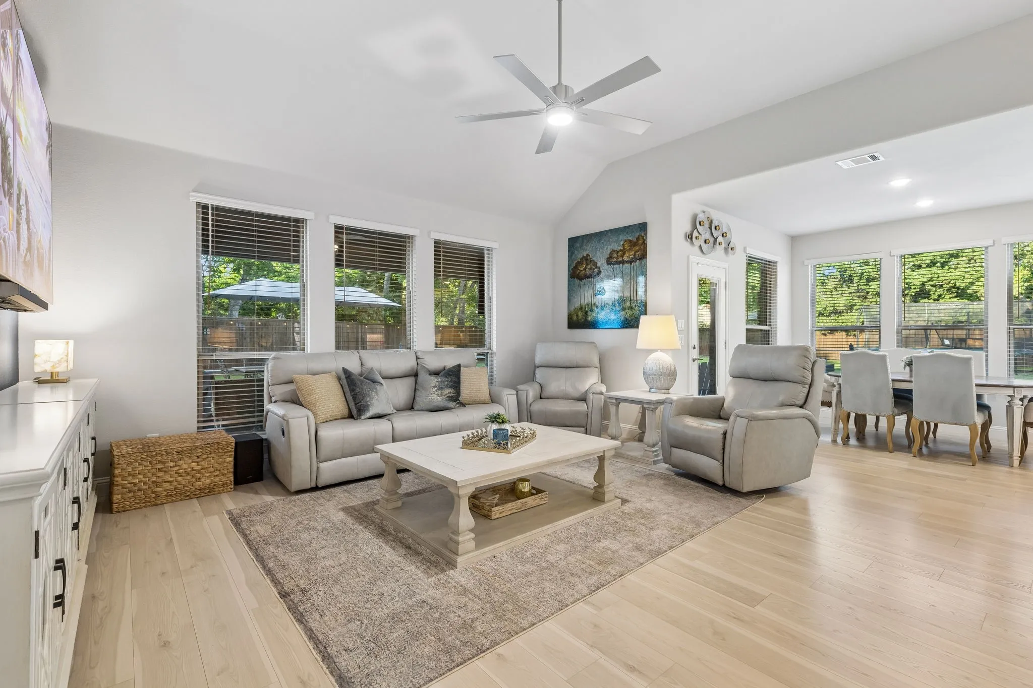 Open-concept living area featuring light wood-finish flooring, a vaulted ceiling, and recessed lighting