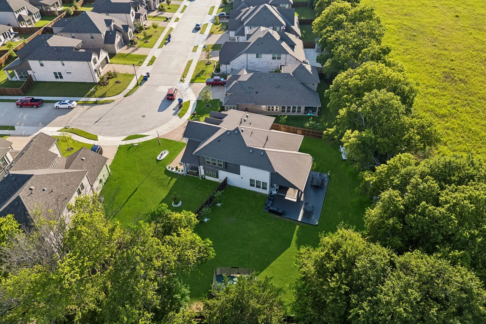 Contemporary residence featuring a two-story design, dark gray roof, and a covered front and back patio with dark-toned decking