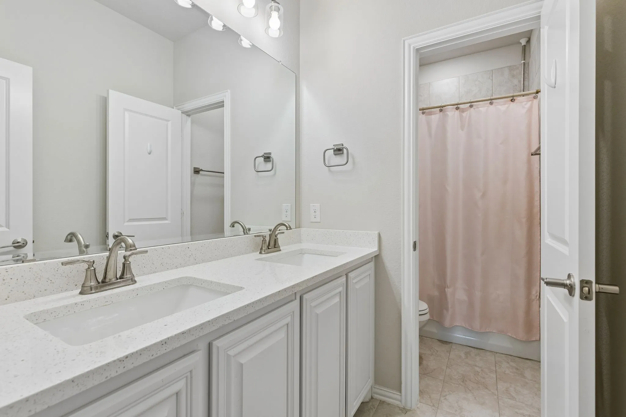 Dual vanity featuring undermount sinks, speckled countertops, and brushed nickel fixtures
