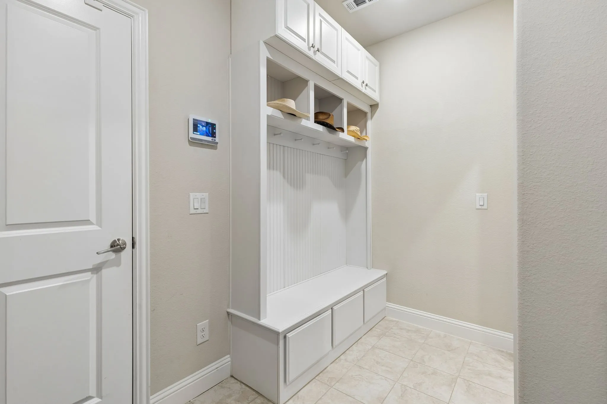 Mud Room, Built-in  storage unit featuring a bench, three lower cabinets, four open cubbies, and upper cabinetry with paneled doors