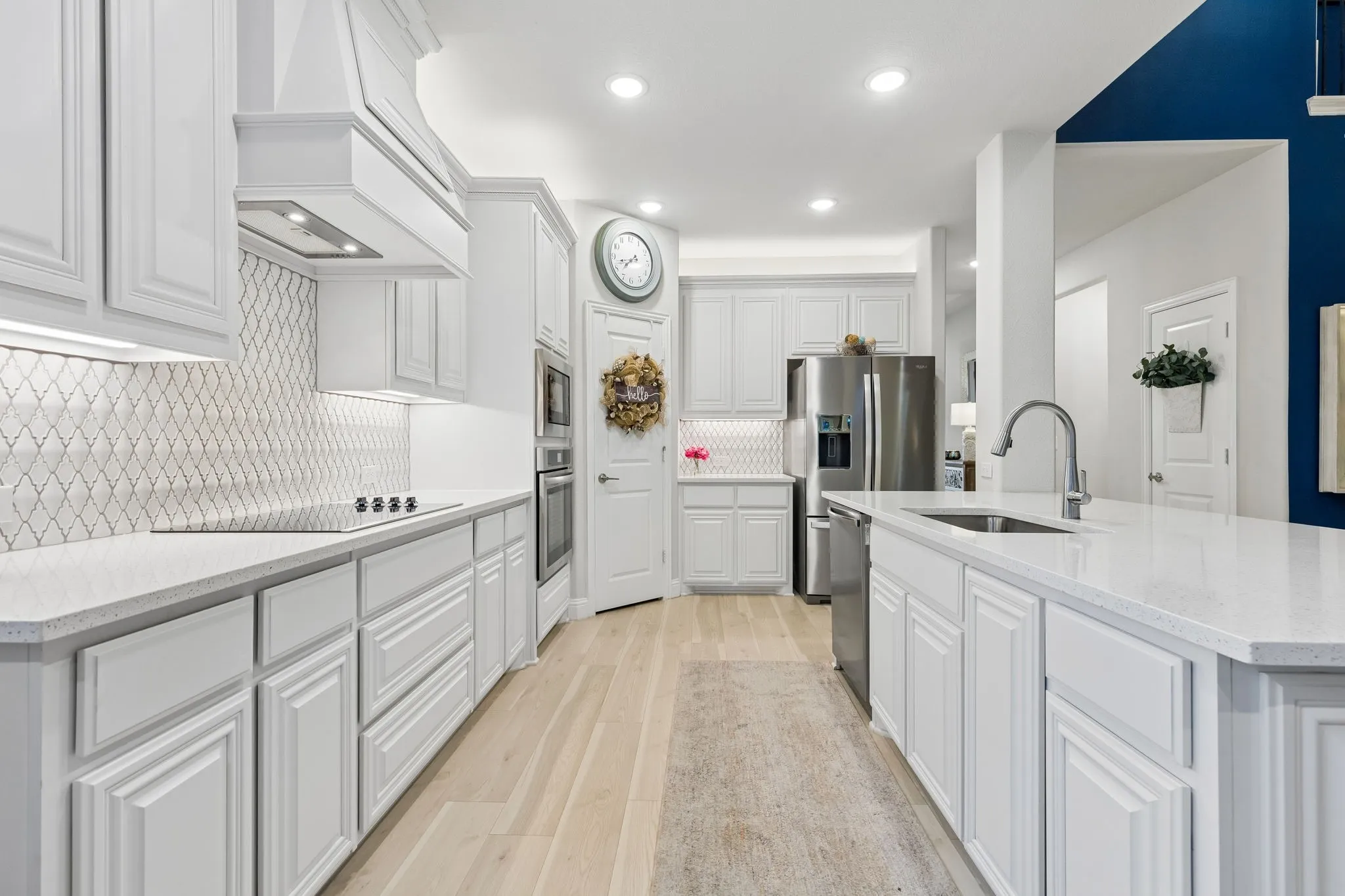 Modern kitchen featuring white shaker cabinetry, light-toned wood-finish flooring, and white  countertops