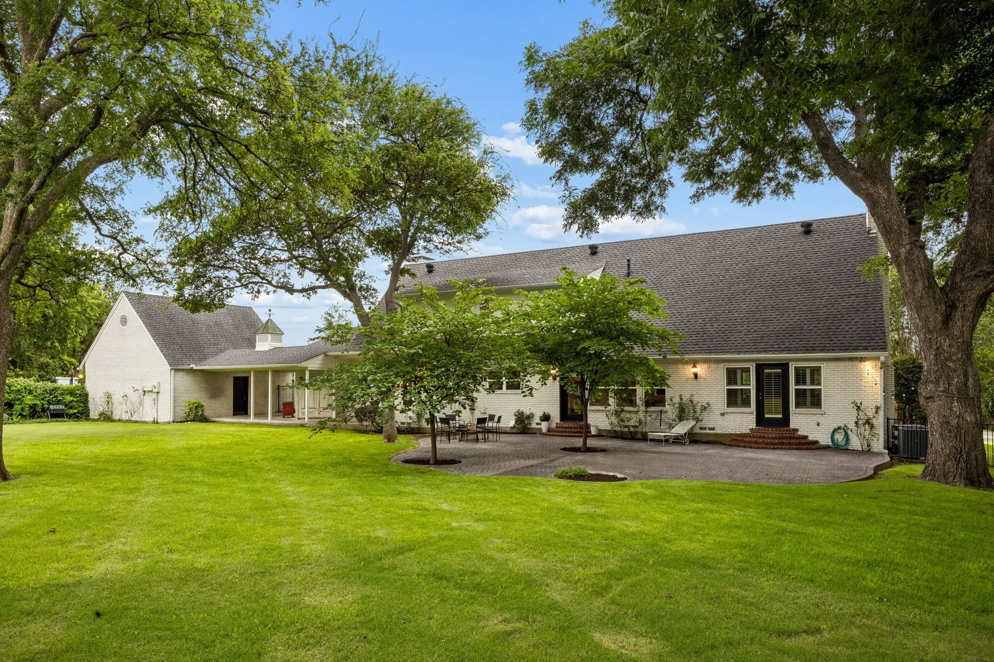 Rear elevation of the home shows the mature trees and extensive patio space of the home.
