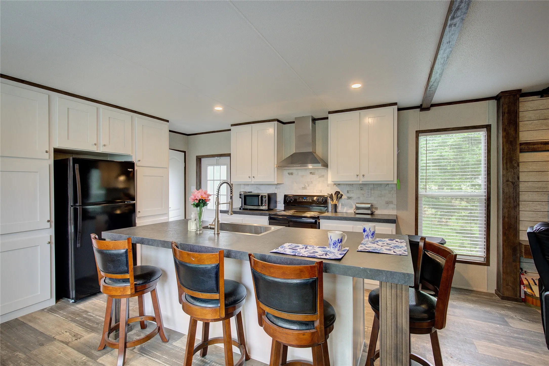 Kitchen has island, breakfast bar, pantry cabinet, electric range with vent hood.
