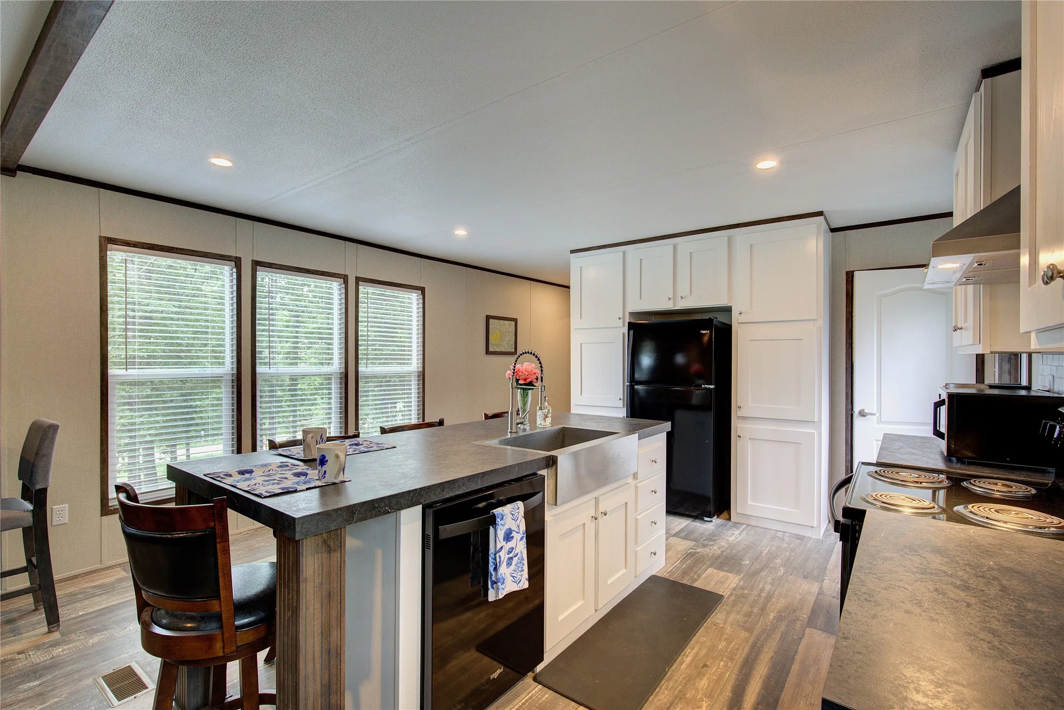 Farmhouse style stainless steel sink, dishwasher, wall of cabinets around fridge