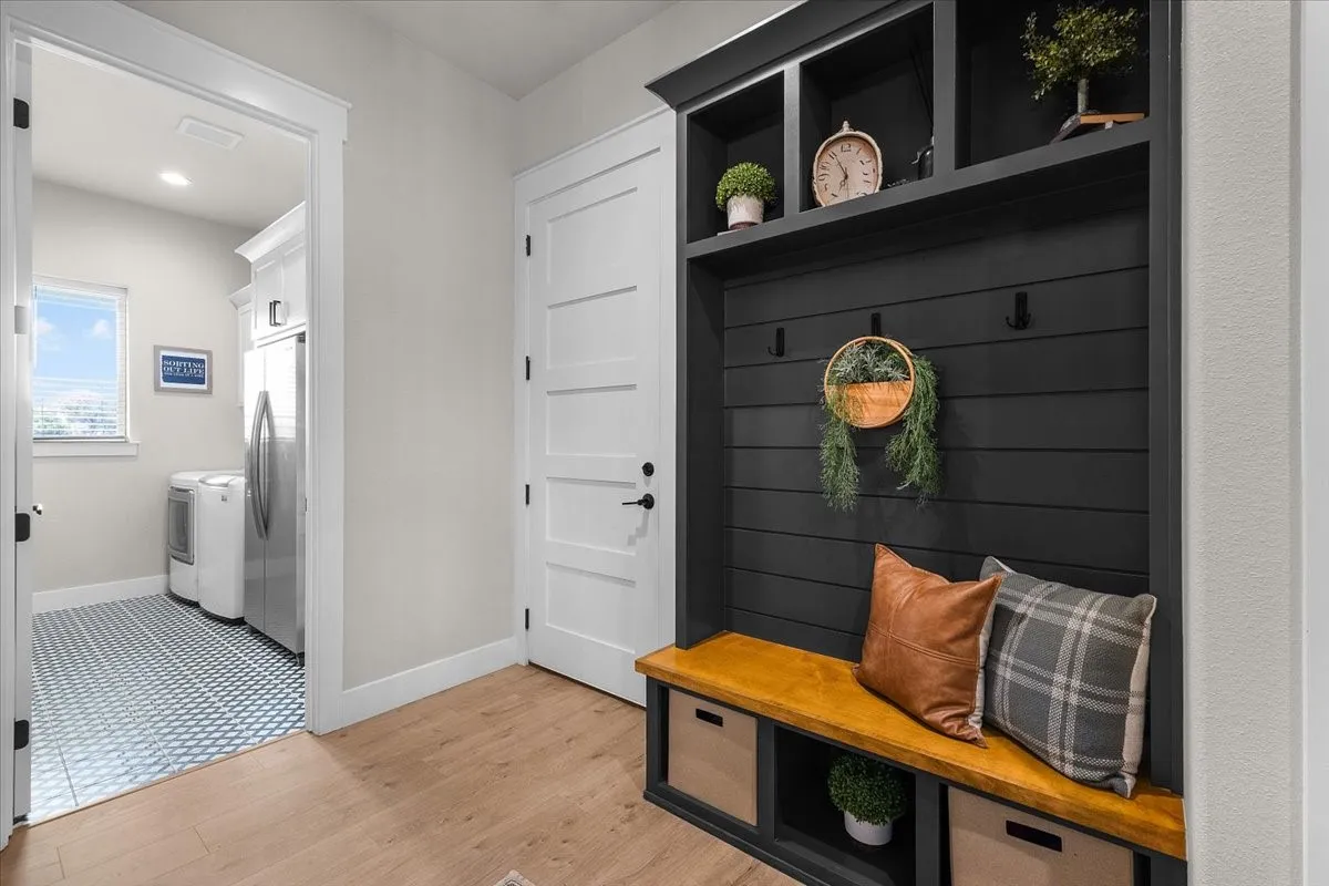 Mudroom just outside garage door with dark shiplap backing, wooden bench seating, and integrated storage cubbies