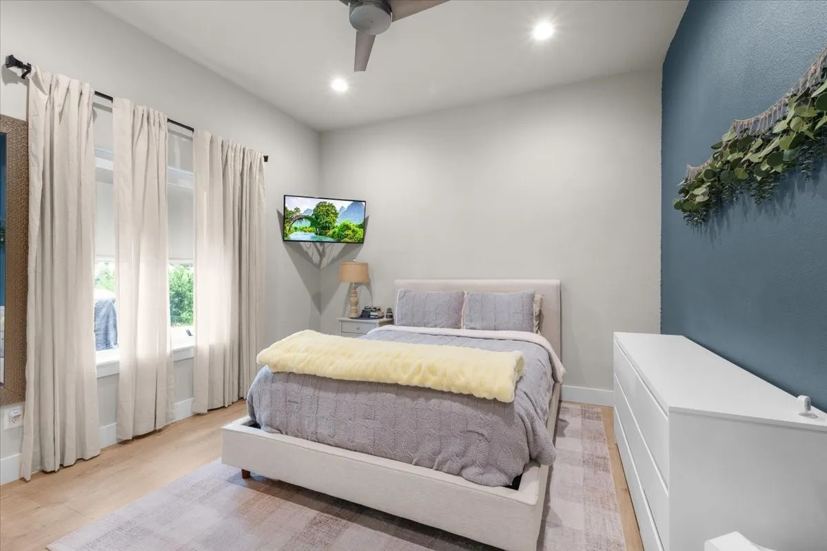 Bedroom featuring recessed lighting, ceiling fan and roller shades.