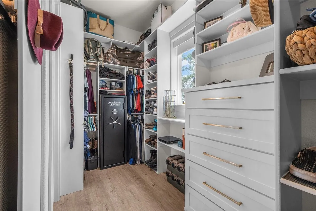 Custom closet system featuring white built-in cabinetry, varied shelving, garment hanging rods, and integrated drawers with brass-tone hardware
