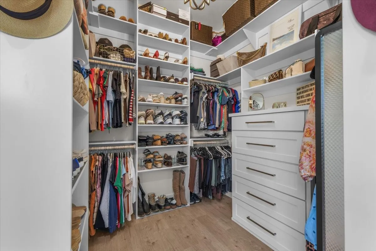 Custom closet system featuring extensive shelving, multiple hanging rods, and built-in drawers with dark hardware