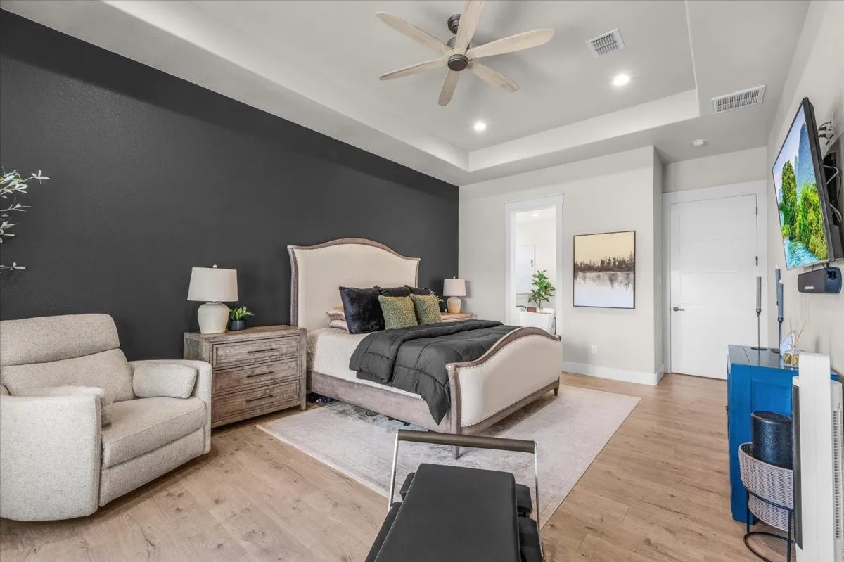 Primary room featuring a tray ceiling with a ceiling fan, recessed lighting, roller shades and accent wall.