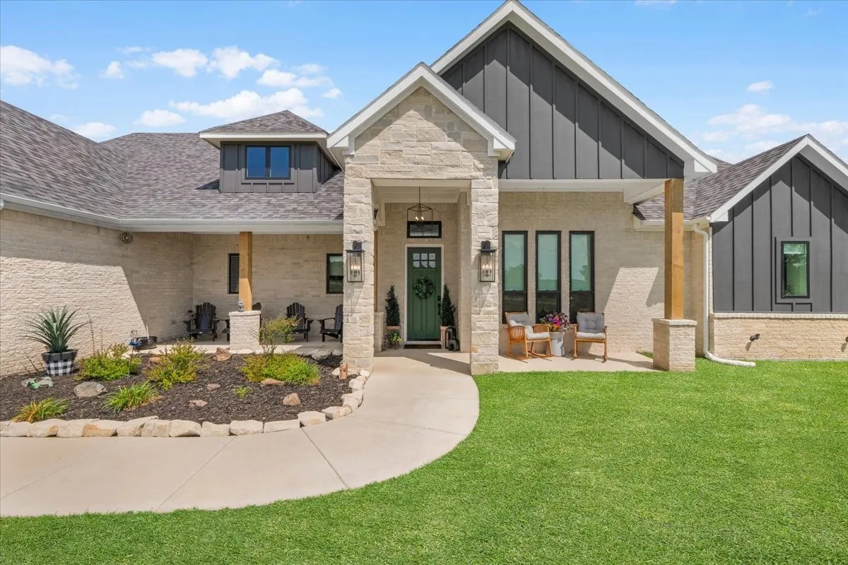 Contemporary exterior featuring light-colored stone, decorative exterior lighting and wood beams.