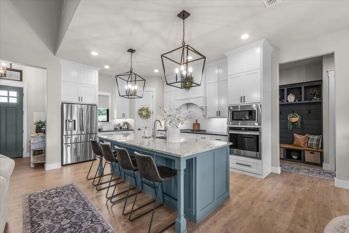 Kitchen featuring stainless steel appliances and white cabinetry that reaches the ceiling.