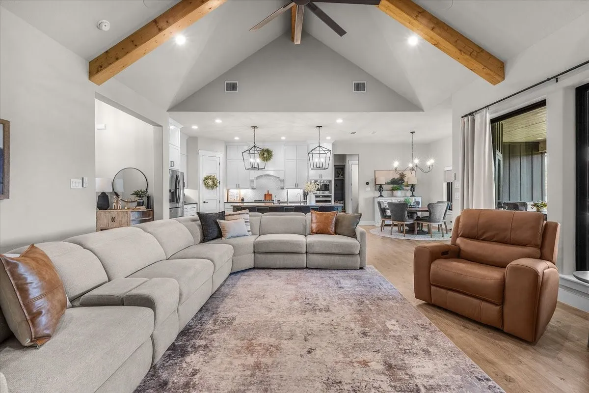 Living room featuring vaulted ceilings with exposed wood beams, recessed lighting, a ceiling fan, and wood tile flooring