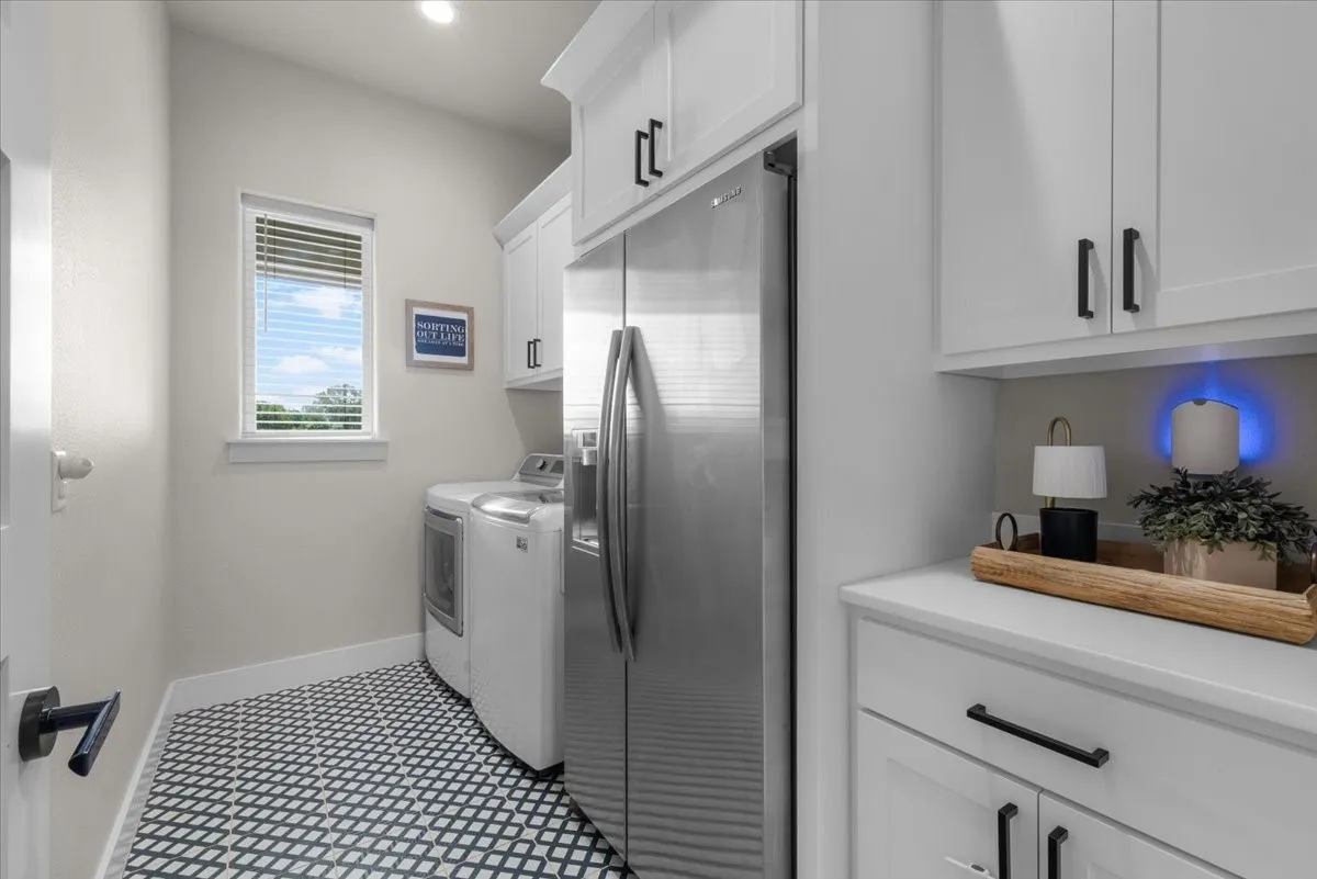 Laundry area featuring white cabinetry and room for an extra refrigerator or freezer.