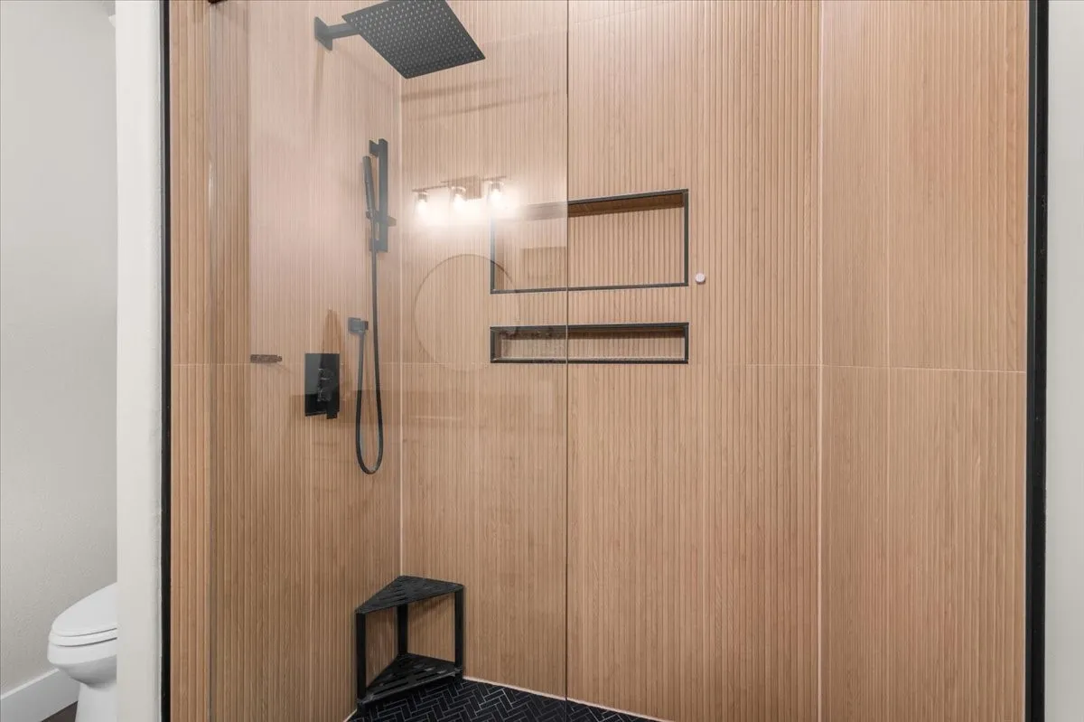 Full bathroom featuring a walk-in shower with wood-look wall tiling, a rain shower head and handheld sprayer