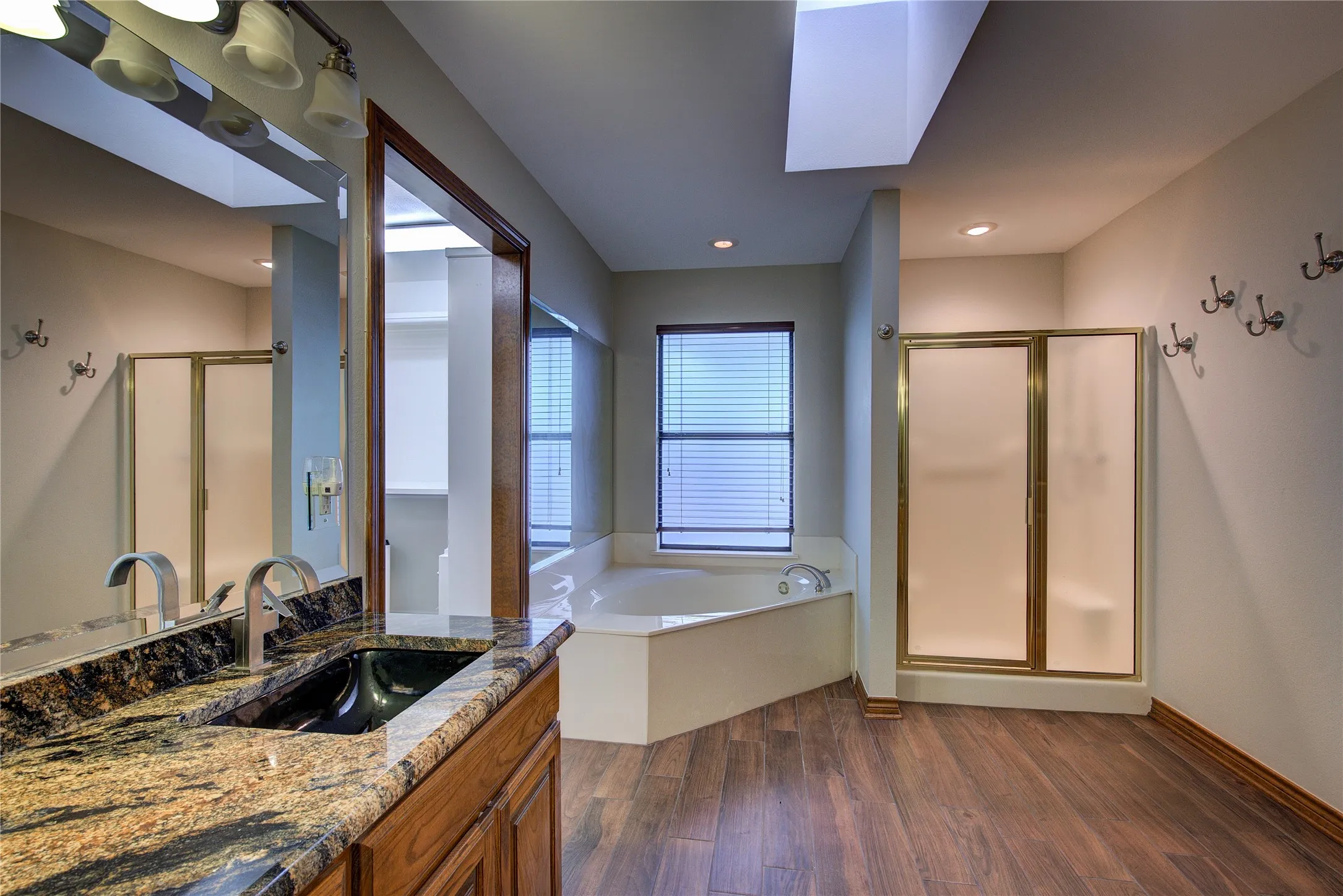 Primary bath has soaking garden tub and separate shower with glass doors and a bench