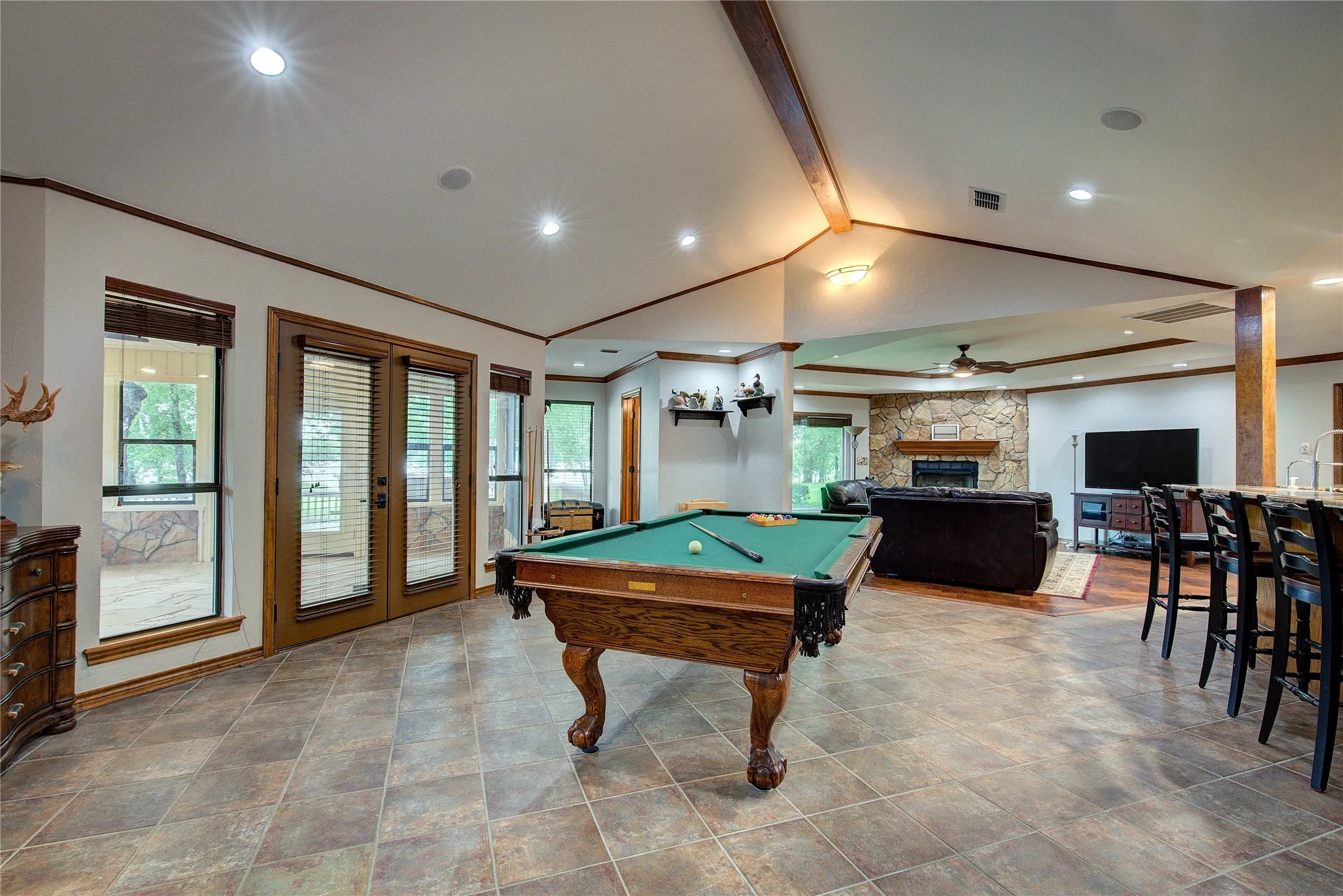 Next is the game room area, with doors to the enclosed sun porch and vaulted ceiling; open to the kitchen and living room