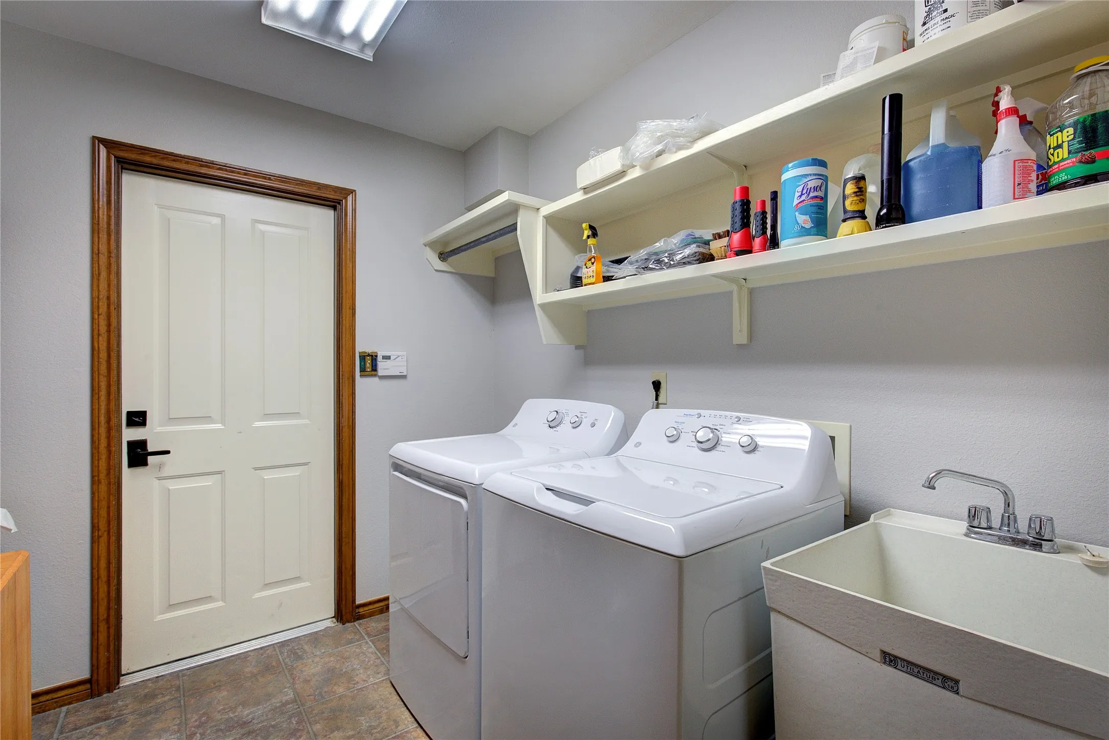 Utility room off garage has sink, cabinet, counter, hanging space or space for freezer.