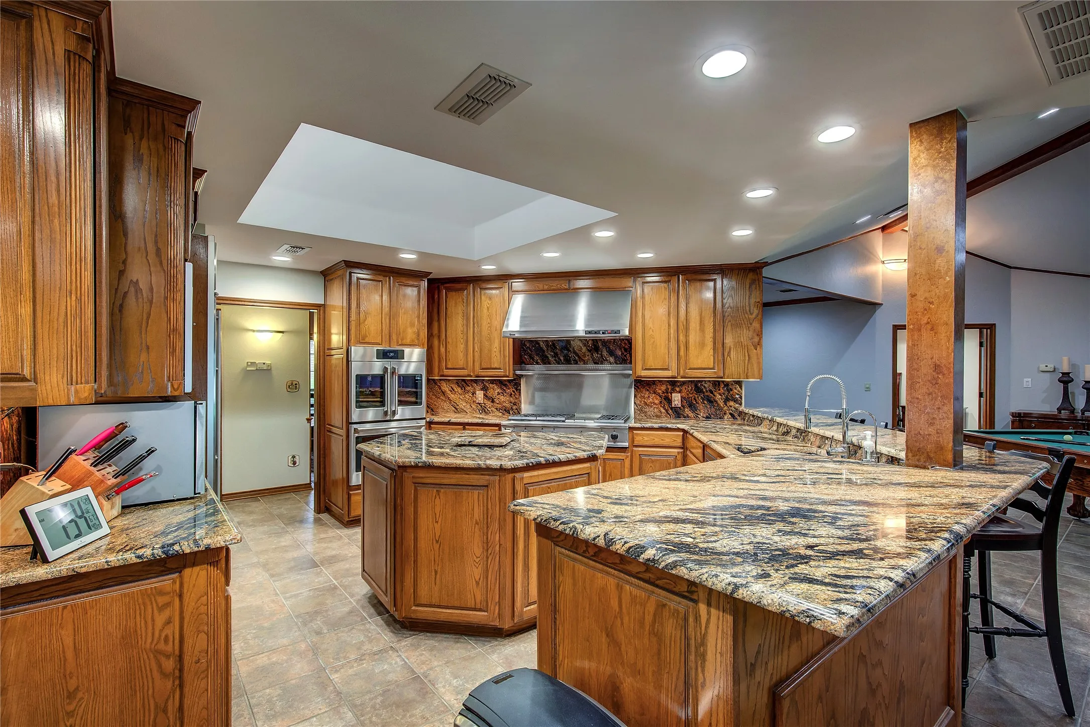 Enormous chef's kitchen has breakfast bar, kitchen island, granite counters, custom wood cabinets