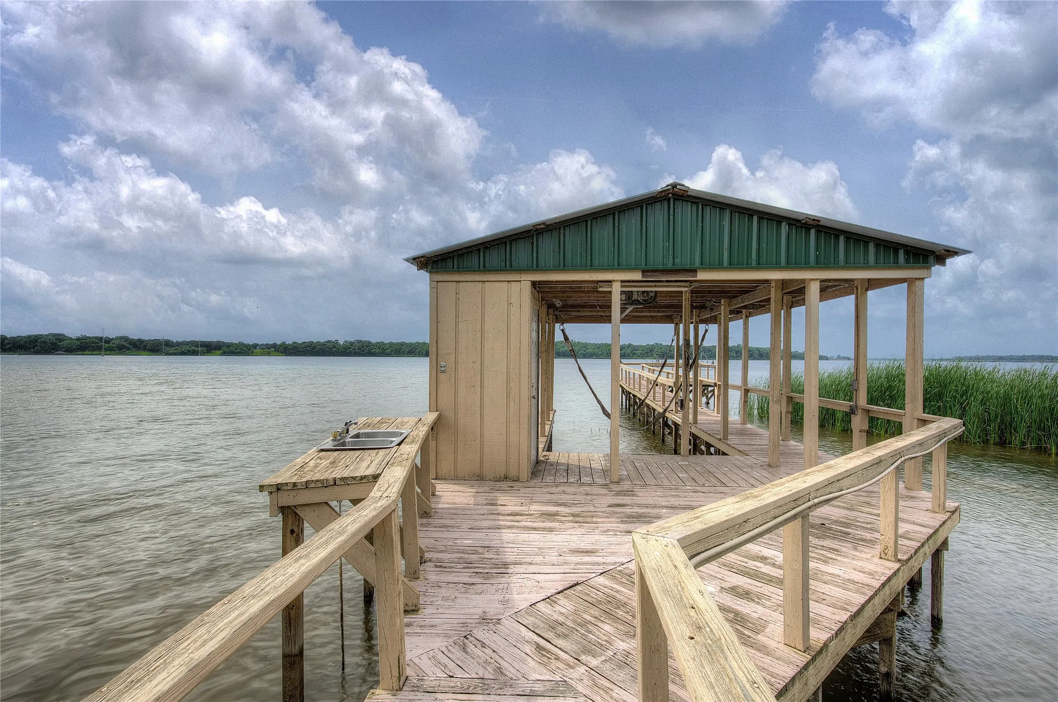 Private dock with covered power boat lift, open deck over the water, fish cleaning station, storage closet.