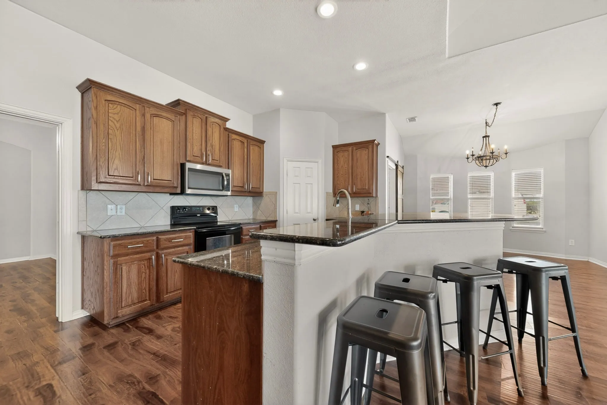 Kitchen featuring wood cabinetry, stainless steel microwave, black electric range, and dark countertops