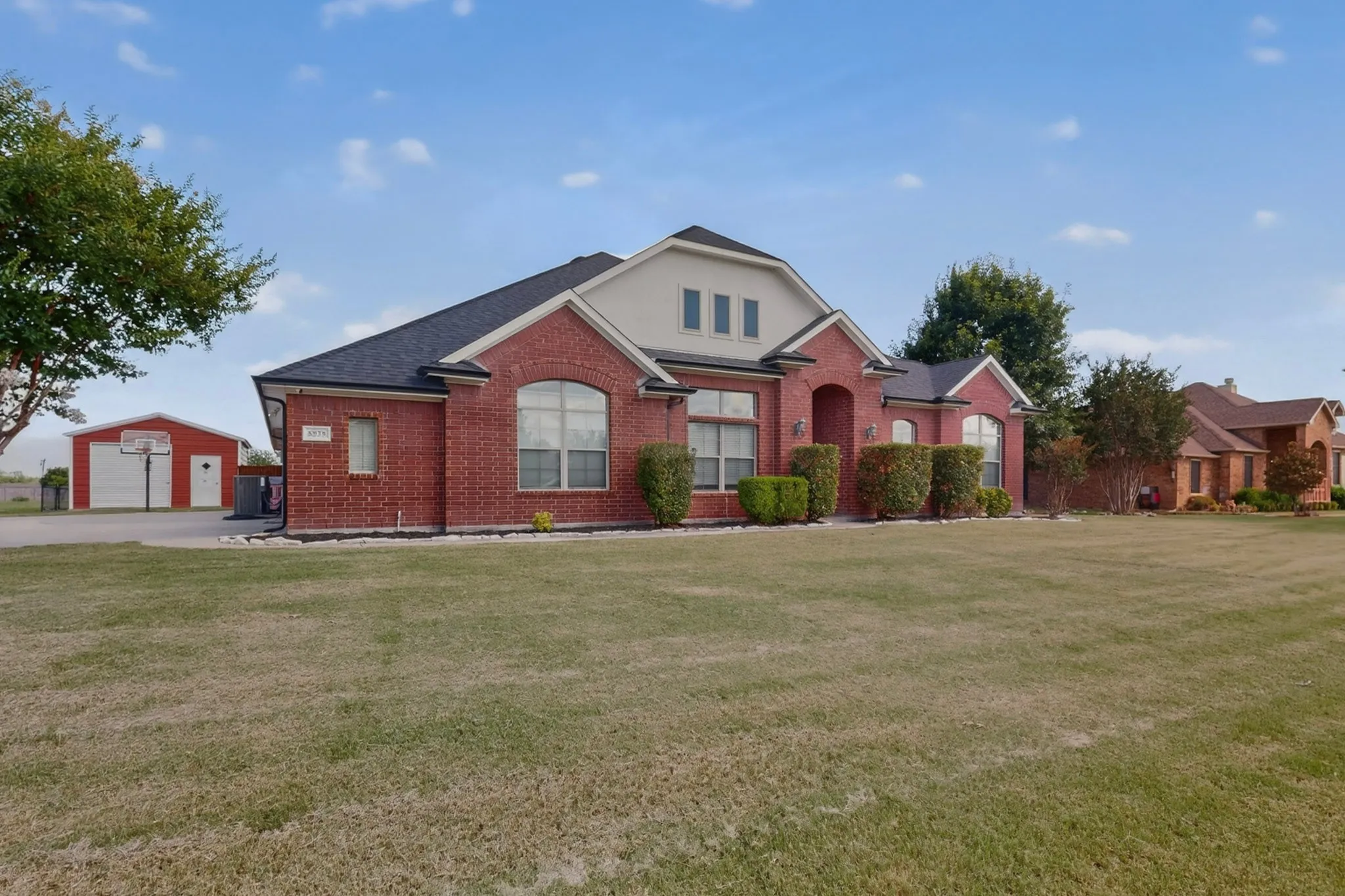 Brick exterior with arched window accents and a dark shingle roof