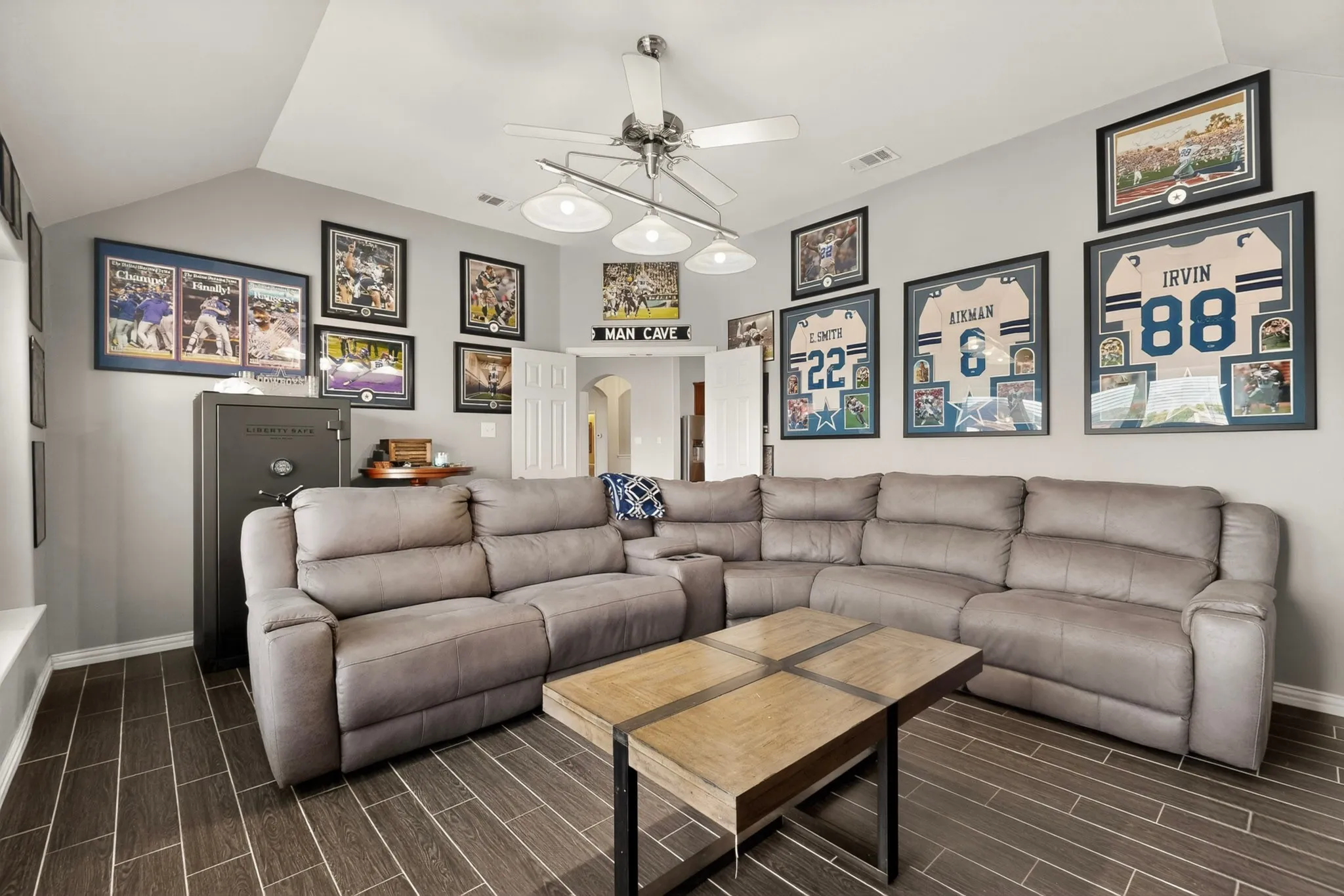 Vaulted ceiling room featuring wood-finish flooring, light gray wall tones, and a ceiling fan with integrated lighting