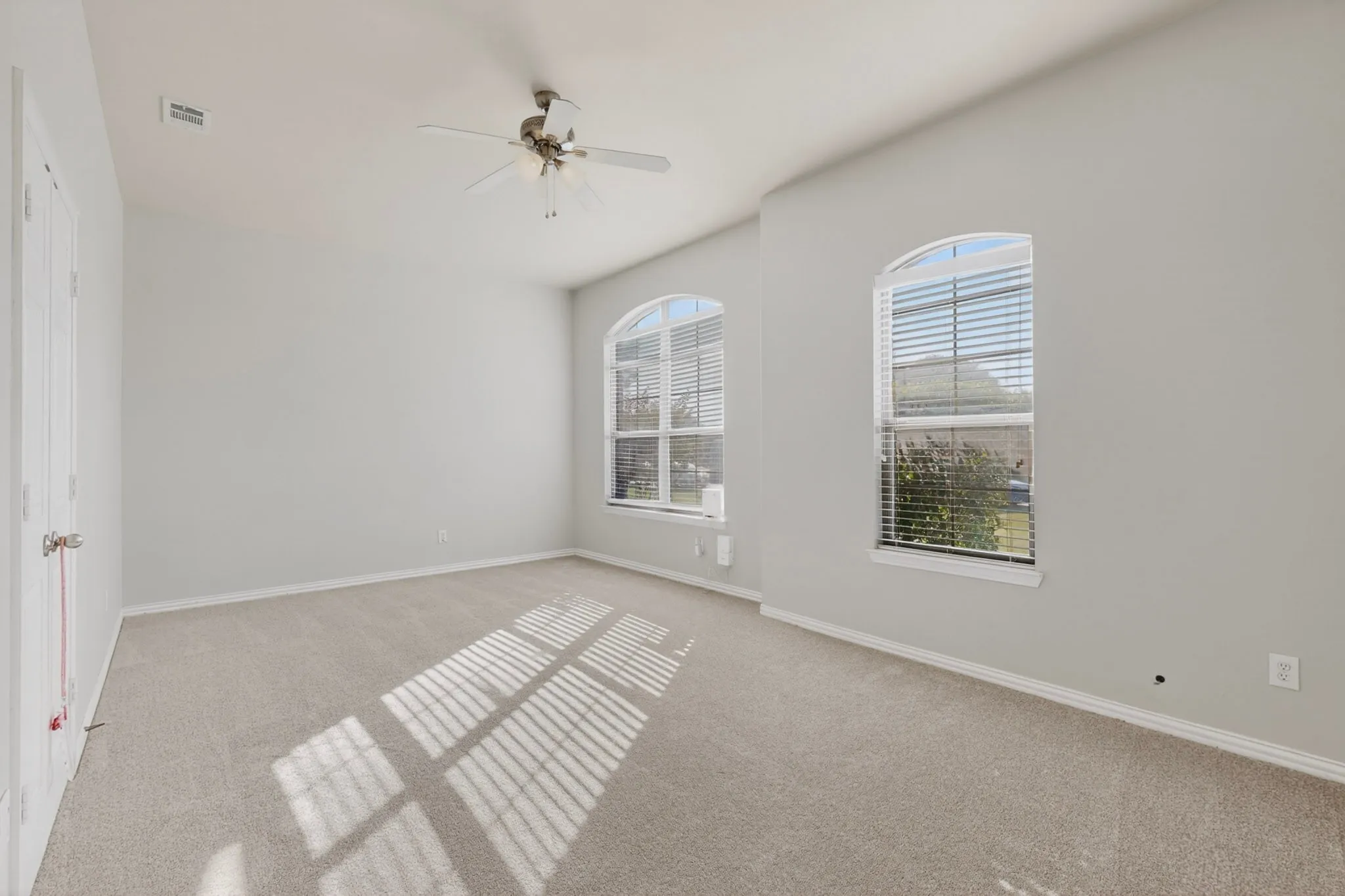 Spacious room featuring neutral carpeting, light gray wall paint, and white trim
