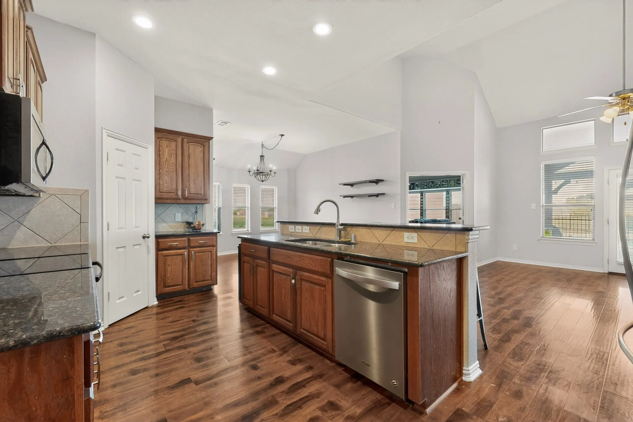 Kitchen featuring wood-finish flooring, dark wood cabinetry, and granite countertops