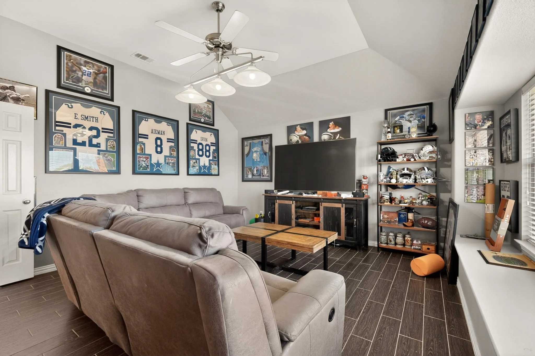 Spacious room featuring wood-finish flooring, a vaulted ceiling, and a ceiling fan with integrated lighting