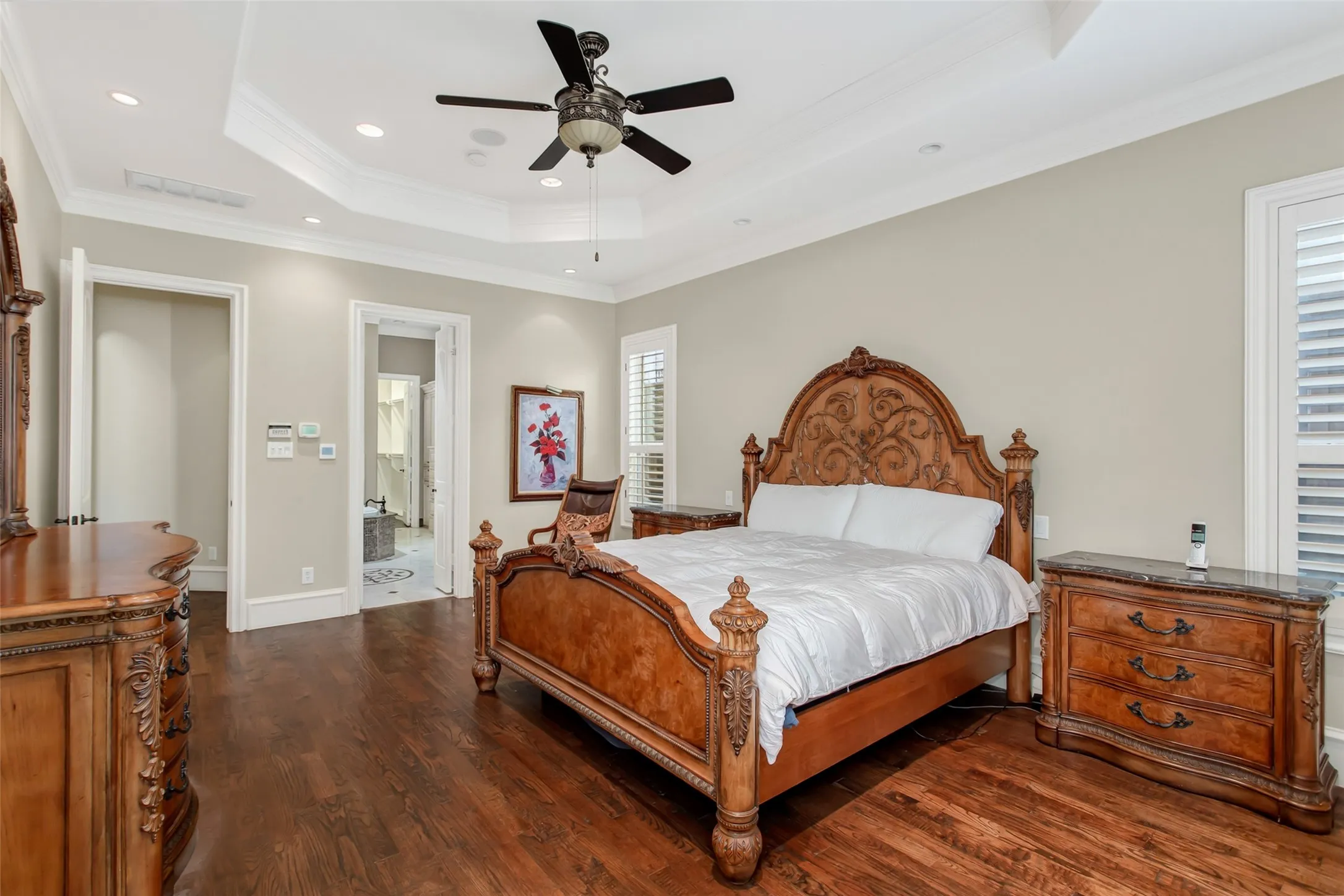 The oversized owner's suite combines timeless craftsmanship with everyday comfort, showcasing hardwood flooring, recessed lighting, custom ceiling details, and a peaceful, light-filled atmosphere.